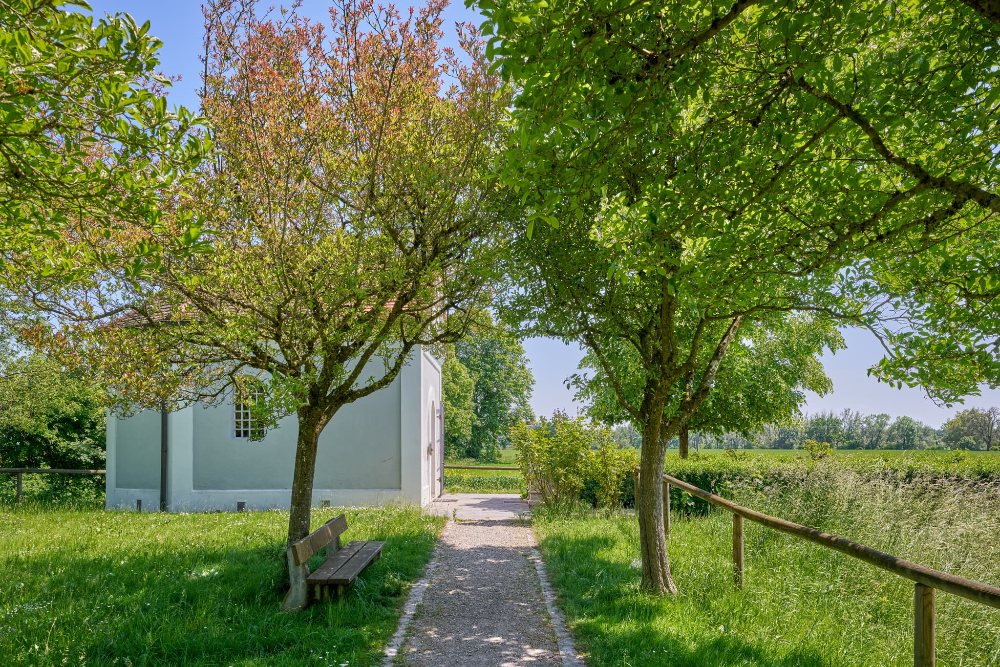 Kronwidl Kapelle in Ecksberg Altmühldorf, Mühldorf am Inn, Oberbayern, Deutschland. Ein Weg führt zur Kapelle, umgeben Bäumen, Bank, grünen Wiesen.