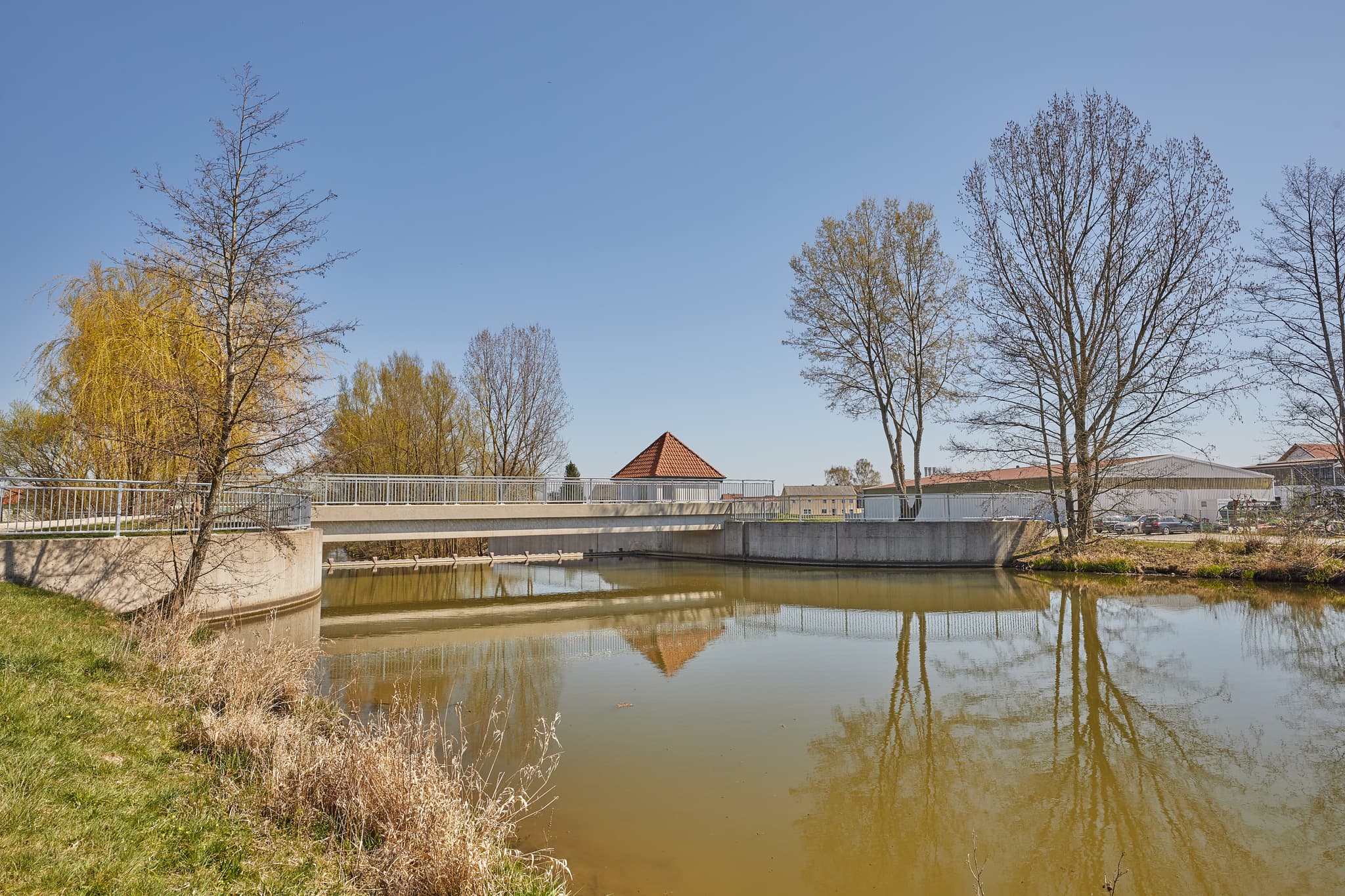Brücke über die Rott, Unterdietfurt im Landkreis Rottal-Inn, Region Holzland, Niederbayern, Deutschland. Die ruhige Landschaft spiegelt Bäume wider.