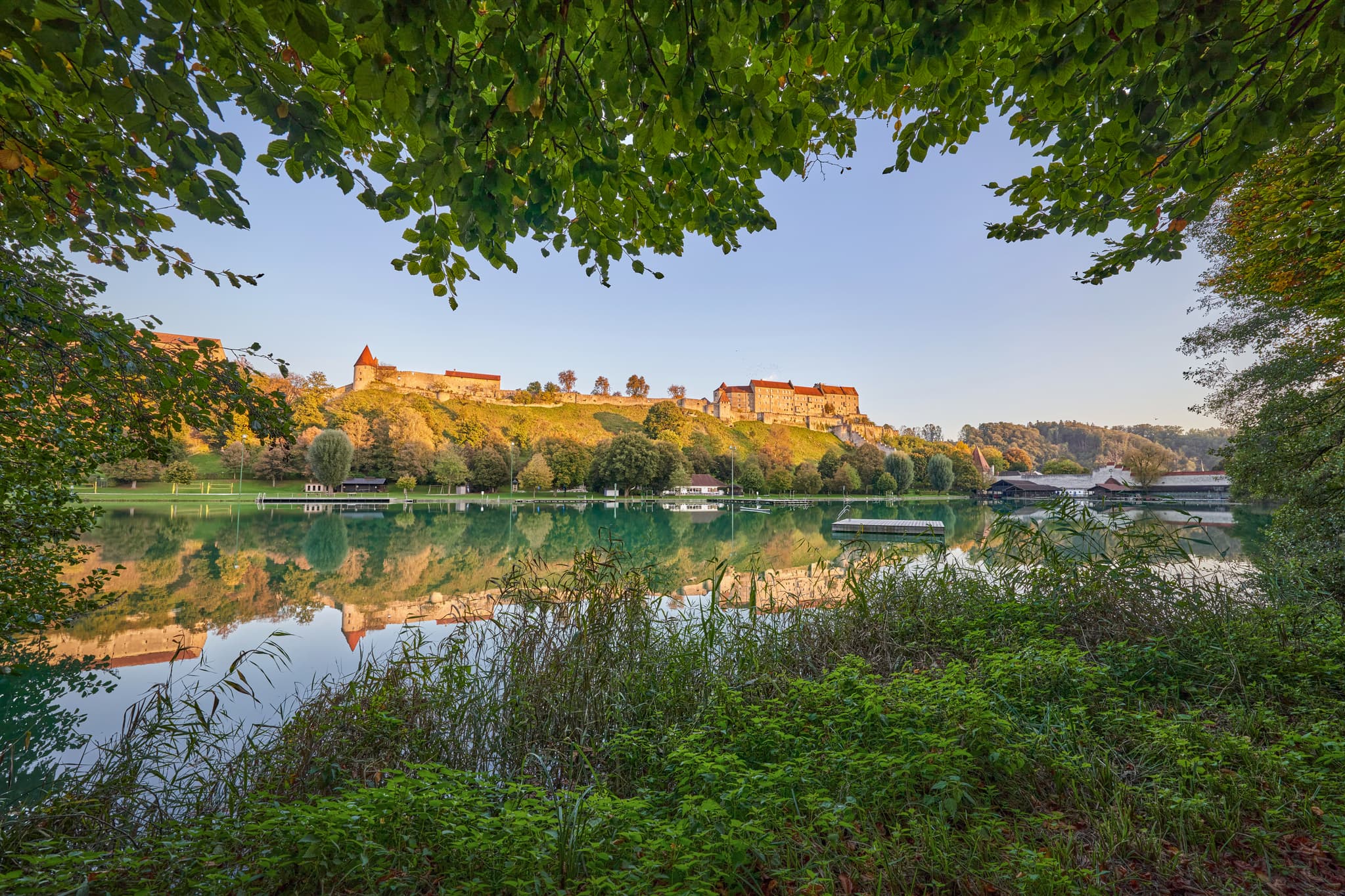 Wöhrsee in Burghausen mit Burg Burghausen auf dem Hügel. Die grüne Landschaft des Landkreises Altötting, Oberbayern, Region Inn-Salzach. Spiegelung im See.