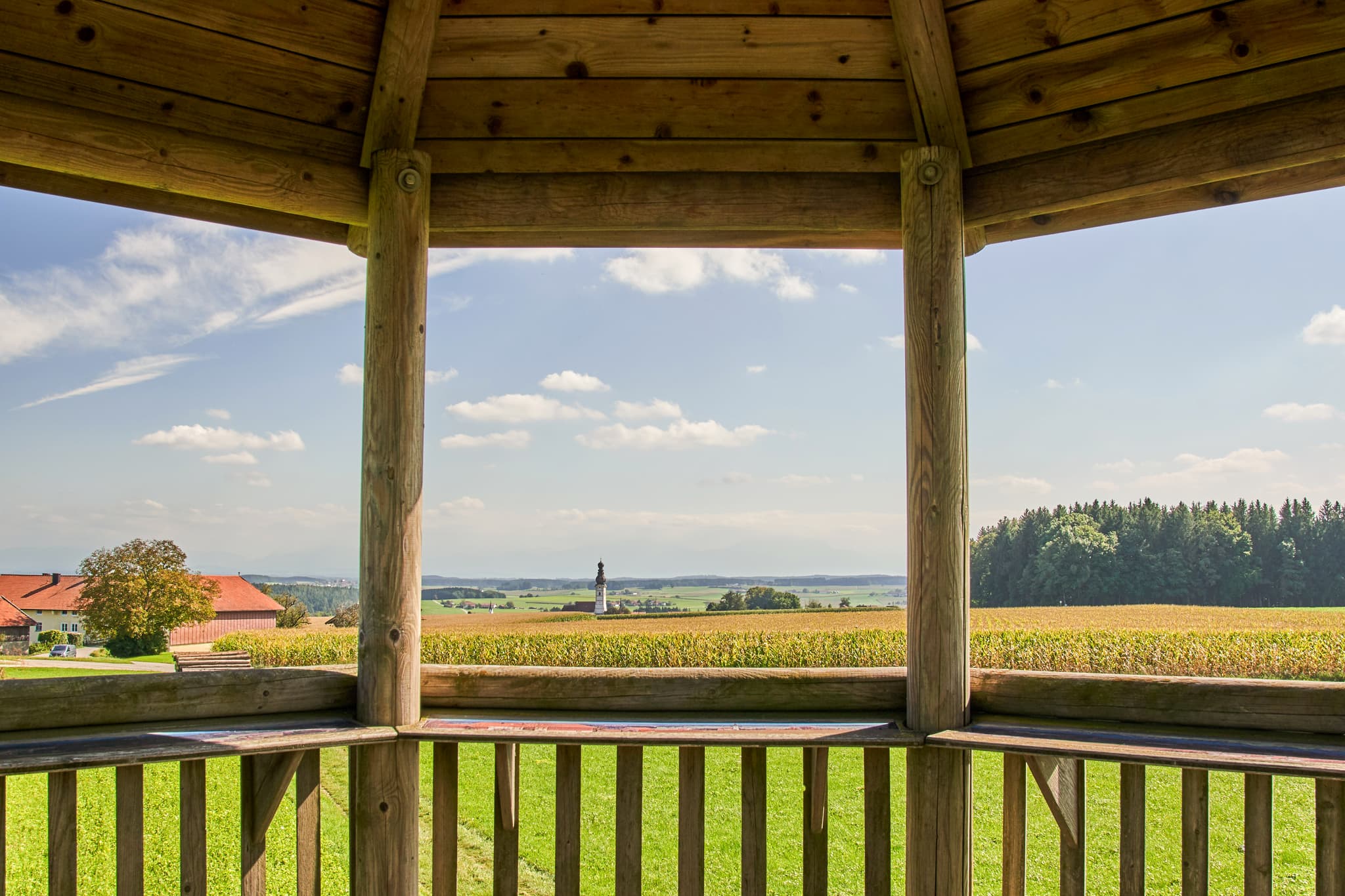 Aussichtsturm in Schnaitsee, Landkreis Traunstein, Oberbayern, Deutschland. Zeigt Chiemgauer Landschaft mit Feldern und Wäldern bei blauem Himmel.