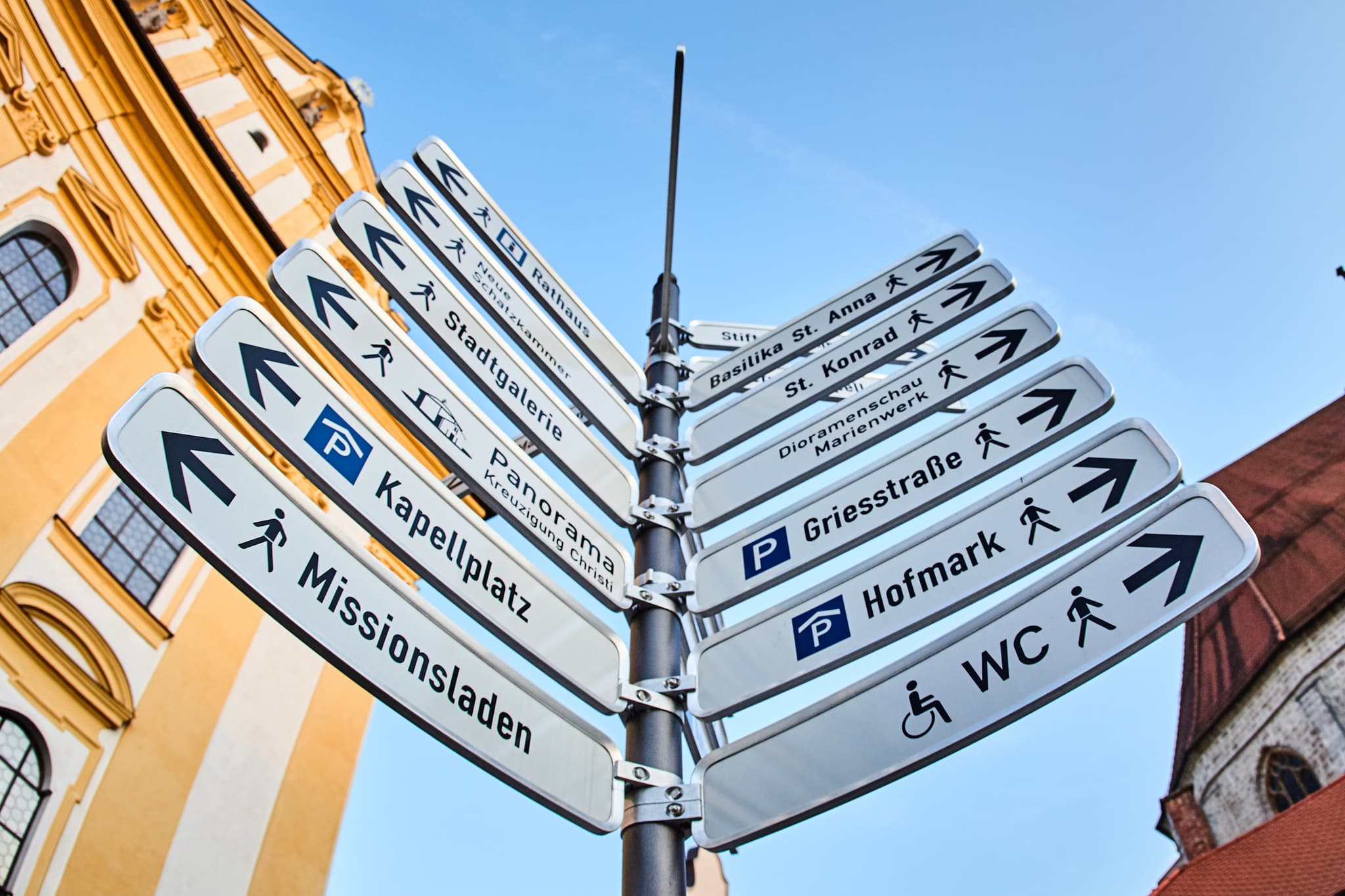 Wegweiser am Kapellplatz in Altötting, Landkreis Altötting, Oberbayern, Region Inn-Salzach, Deutschland. Er zeigt verschiedene Ziele im historischen Zentrum.