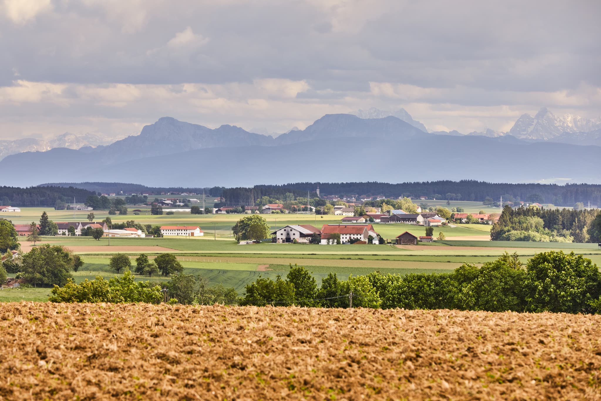 Weitläufige Landschaft bei Garching, Altötting, Oberbayern. Blick über Felder, Häuser und Berge. Typische Szenerie der Region Inn-Salzach, Deutschland.