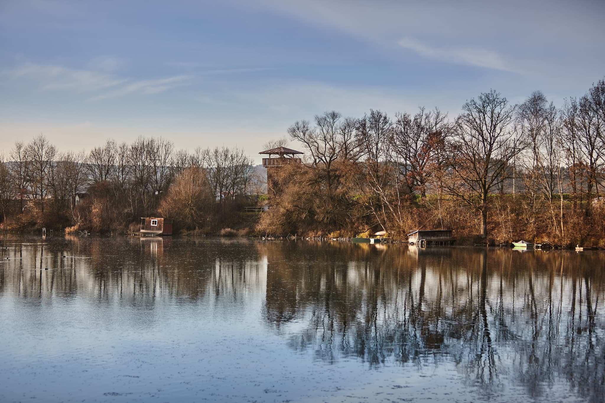 Der Aussichtsturm Vogelturm in Ering am Inn, Landkreis Rottal-Inn, Niederbayern, Deutschland. Der Turm spiegelt sich im Gewässer, umgeben von Bäumen am Ufer.