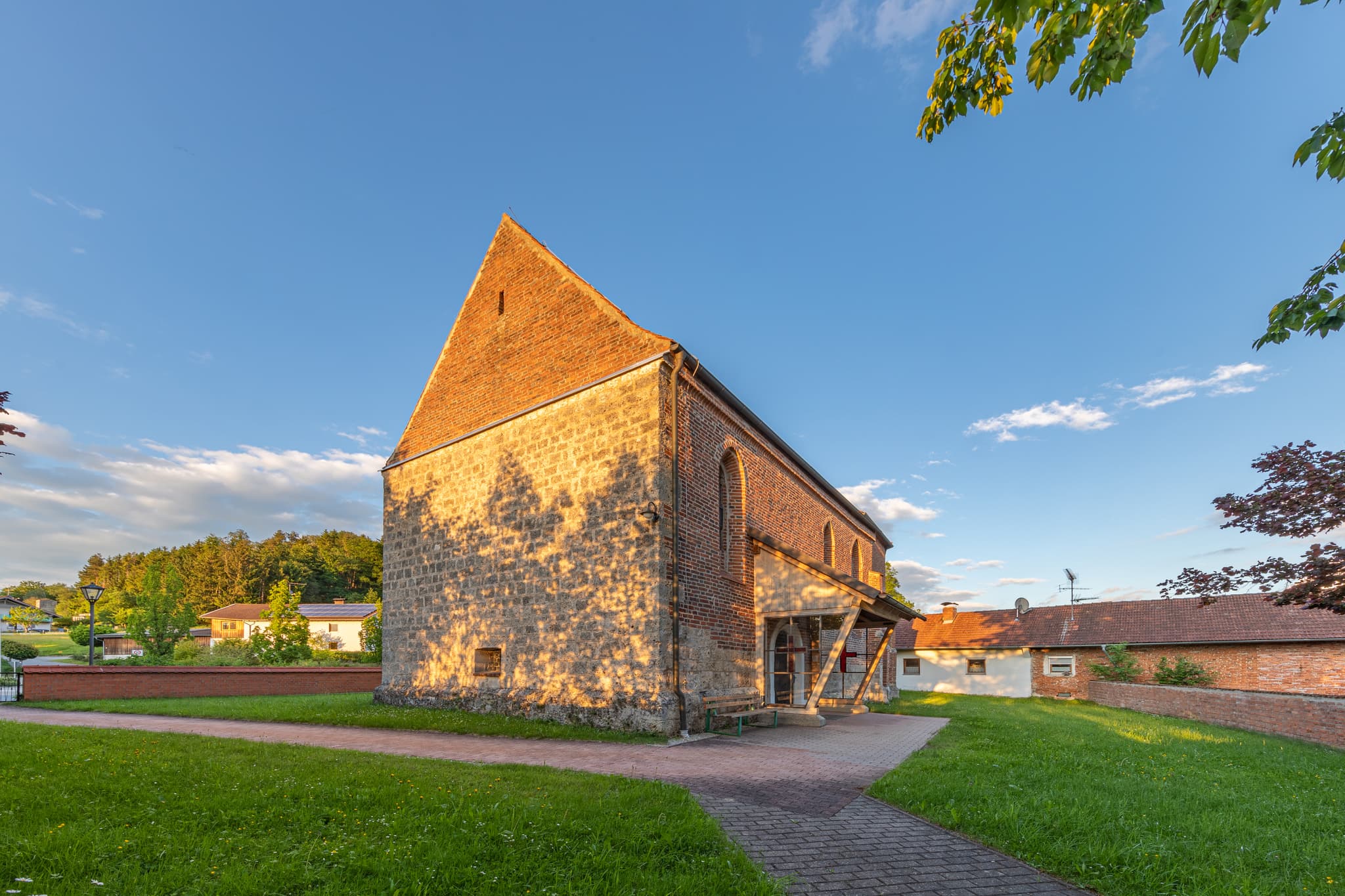 Gumpersdorf, Zeilarn, Rottal-Inn, Niederbayern, Deutschland: Filialkirche St. Rupert. Kirche mit Ziegelgiebel auf Grünfläche im Holzland, beleuchtet Abendsonne.