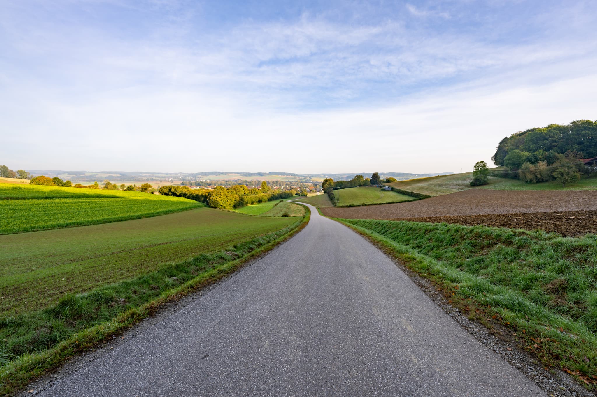 Neudeck Aussicht, Bad Birnbach, Rottal-Inn, Niederbayern. Straße durch Felder, sanfte Hügel im Bäderdreieck, Deutschland. Weite Natur unter klarem Himmel.