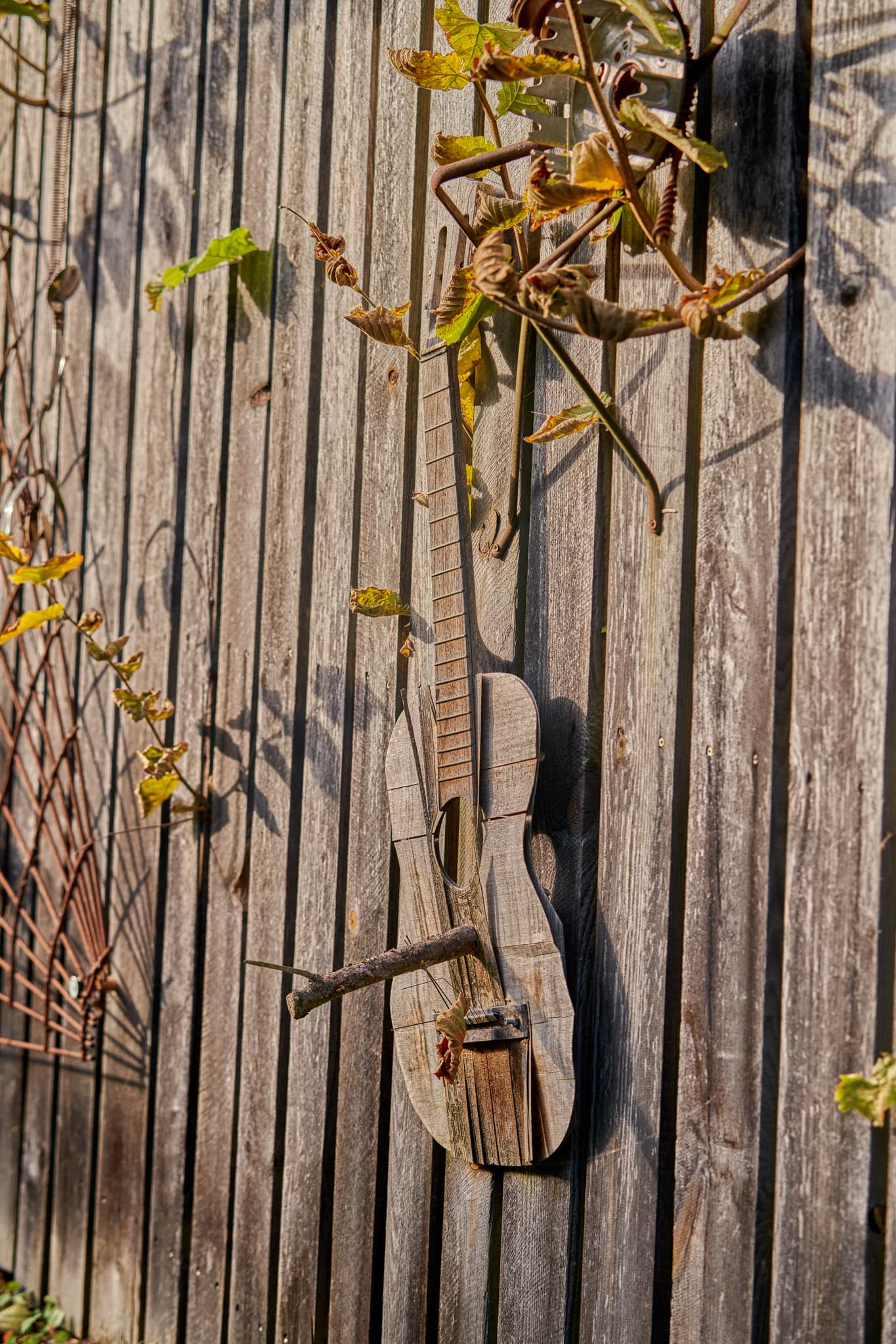 Eine detailreiche Aufnahme eines rustikalen Holzzauns mit einer kreativen Holzgitarre als Dekoration in Schönau, Landkreis Rottal-Inn, Niederbayern, Holzland