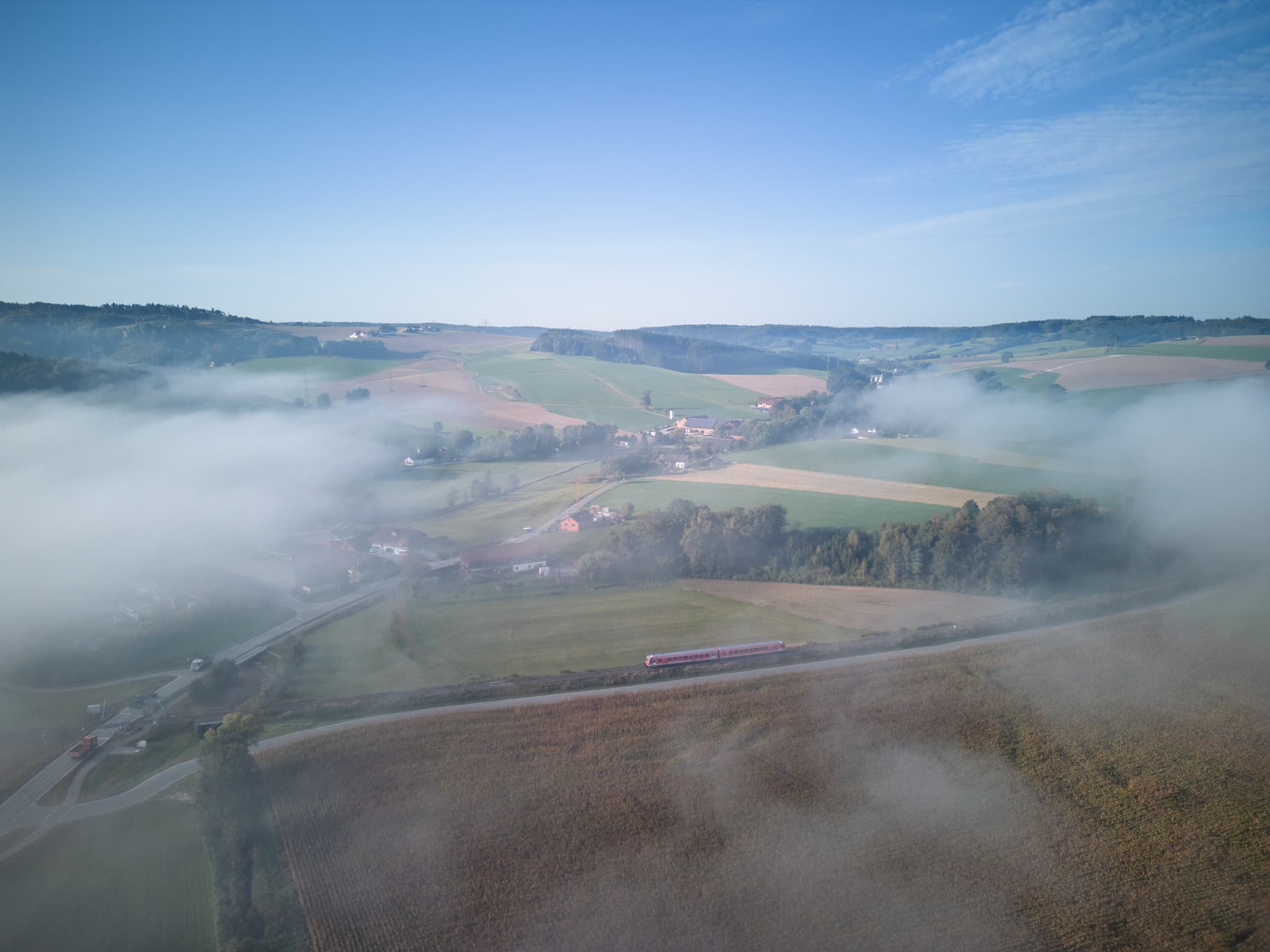 Blick auf Bad Birnbach im Rottal-Inn, Niederbayern, Deutschland. Nebel bedeckt die Felder und Hügel, ein Zug fährt. Ländliche Idylle im Bäderdreieck.