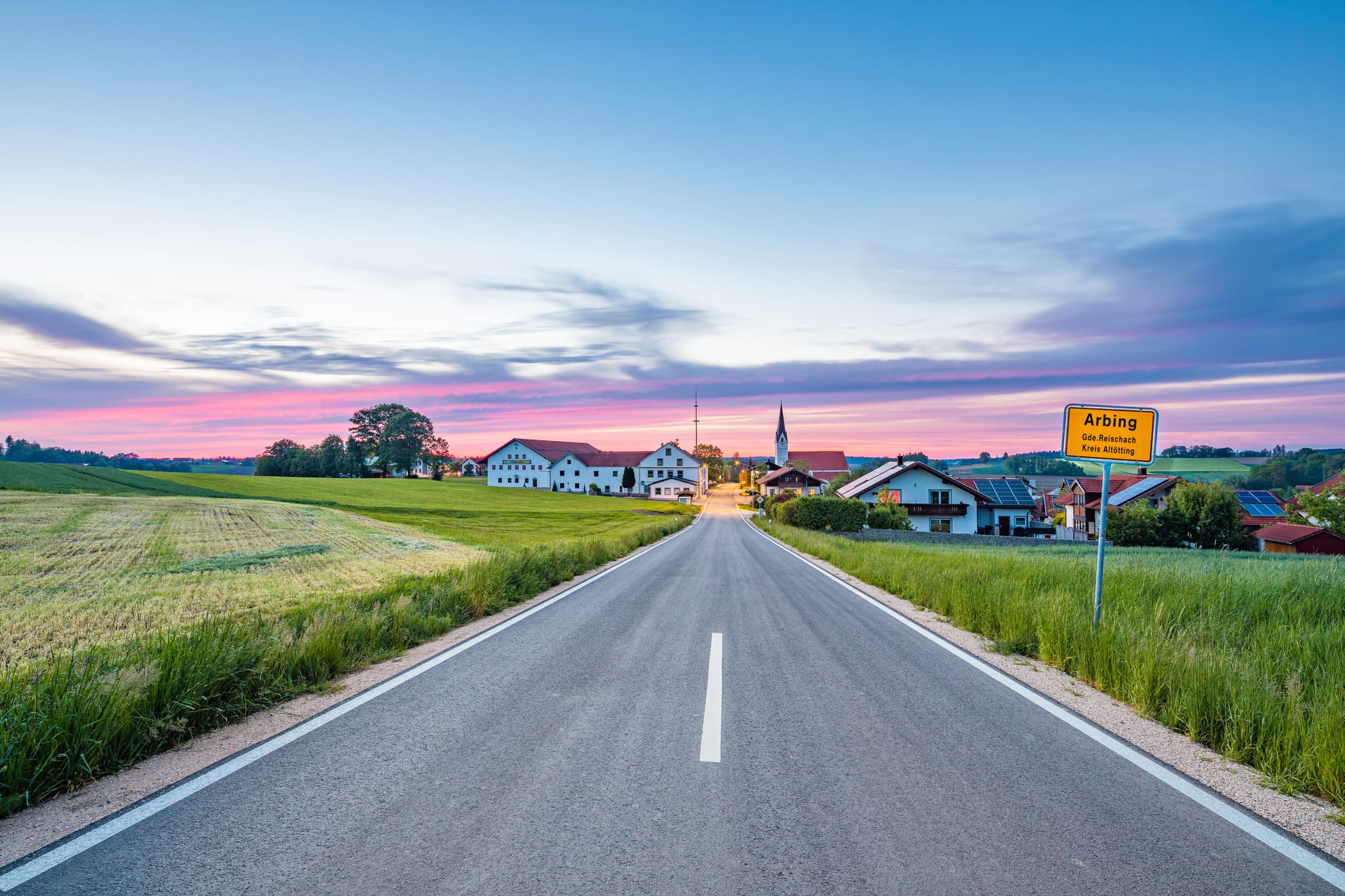 Der Ortseingang von Arbing, einem Ortsteil von Reischach im Landkreis Altötting, Oberbayern, Inn-Salzach, Deutschland, bei malerischem Sonnenuntergang.