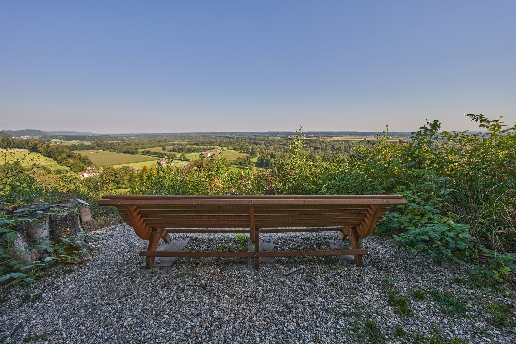 Eine Holzbank bietet einen Ausblick auf die ländliche Landschaft von Reischach im Landkreis Altötting, Oberbayern, Region Inn-Salzach, Deutschland.