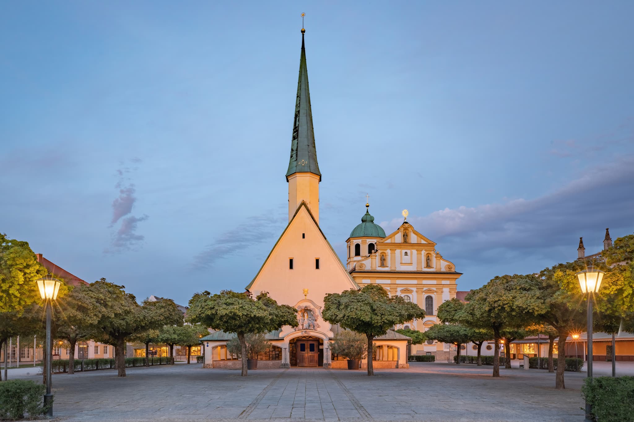 Die Gnadenkapelle prägt den Wallfahrtsort im Landkreis Altötting, Kapellplatz Altötting, Oberbayern. Abendstimmung mit beleuchteten Laternen und Bäumen.