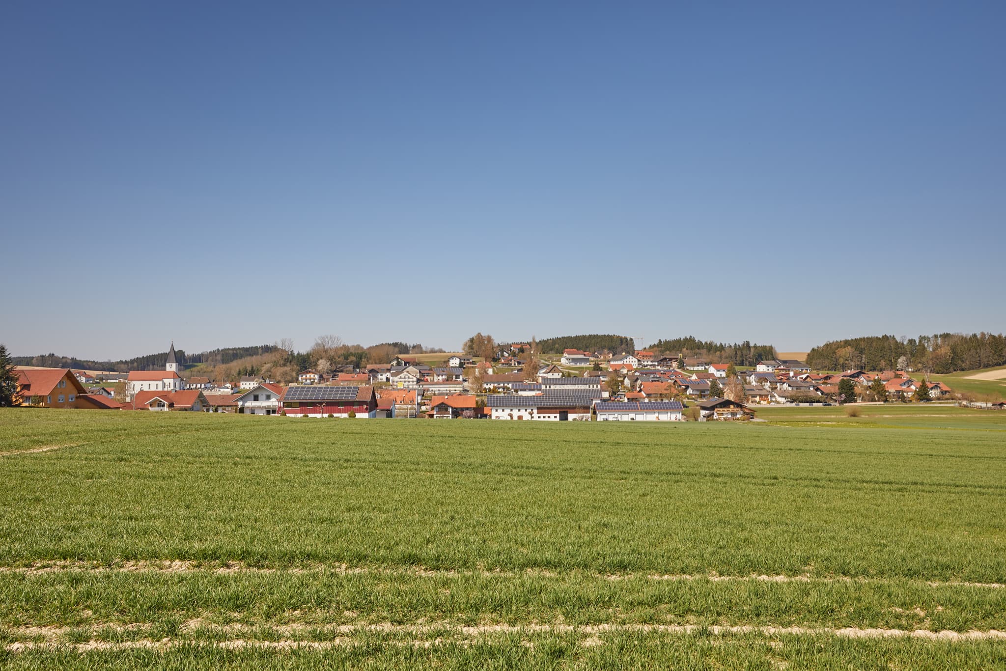 Idyllische Landschaftsaufnahme von Geratskirchen in Niederbayern, Rottal-Inn, Deutschland. Sonnige Aussicht auf die Gemeinde mit Feldern und Häusern.