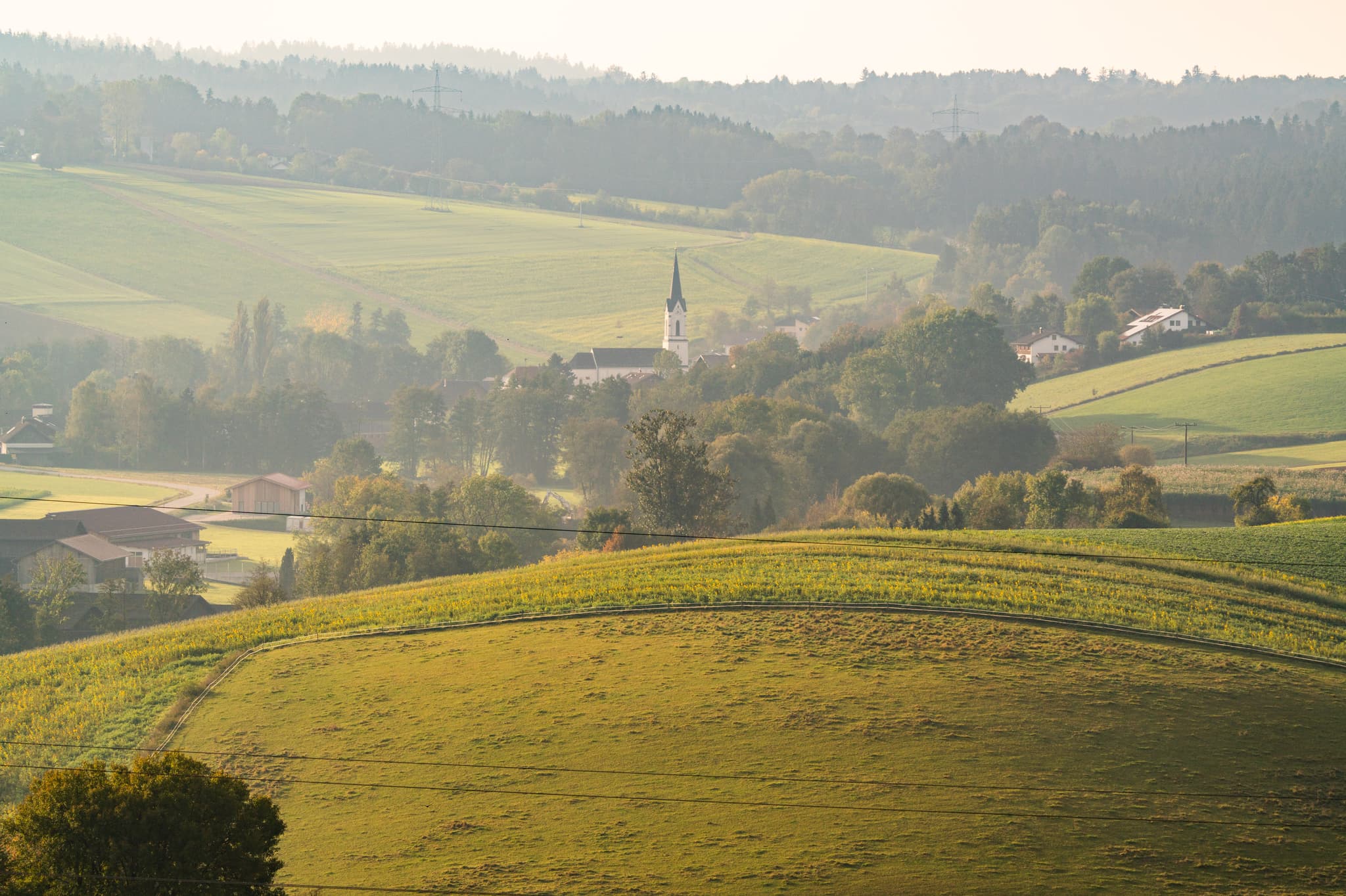 Blick auf sanfte Hügel, weite Felder und ein Dorf mit Kirchturm bei Neudeck Aussicht Asenham, Bad Birnbach, Rottal-Inn, Niederbayern, Bäderdreieck, Deutschland.