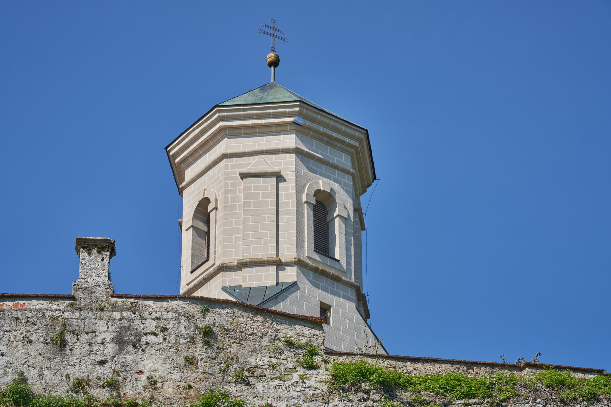 Kirchturm in Raitenhaslach, Gemeinde Burghausen, Landkreis Altötting, Oberbayern, Region Inn-Salzach. Blick auf die obere Turmspitze und Teile der Kirchenmauer.