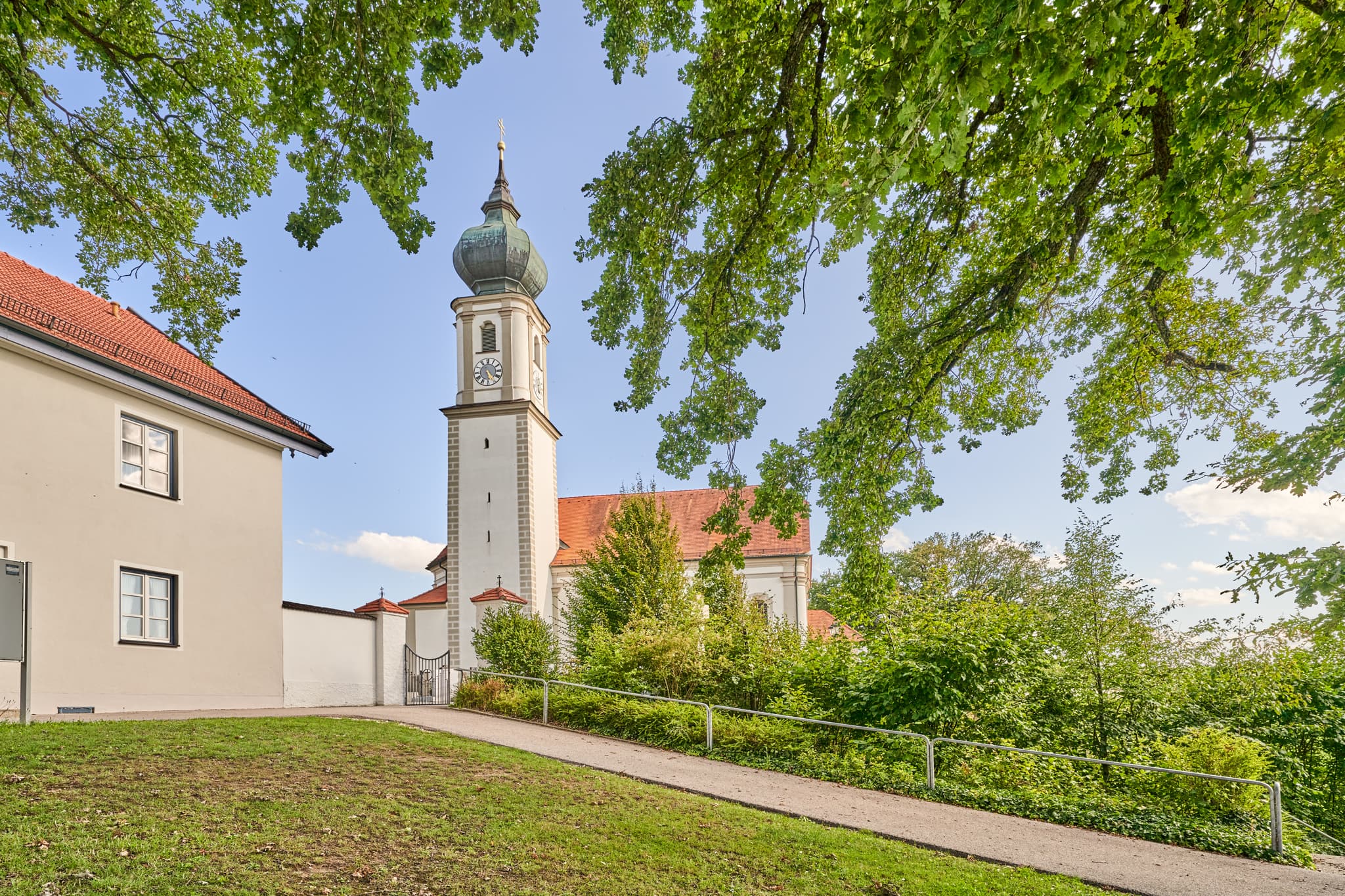 Die Kirche St. Martin in Niedertaufkirchen, Landkreis Mühldorf am Inn, Oberbayern. Historisches Gotteshaus mit Zwiebelturm, umgeben von Grün.