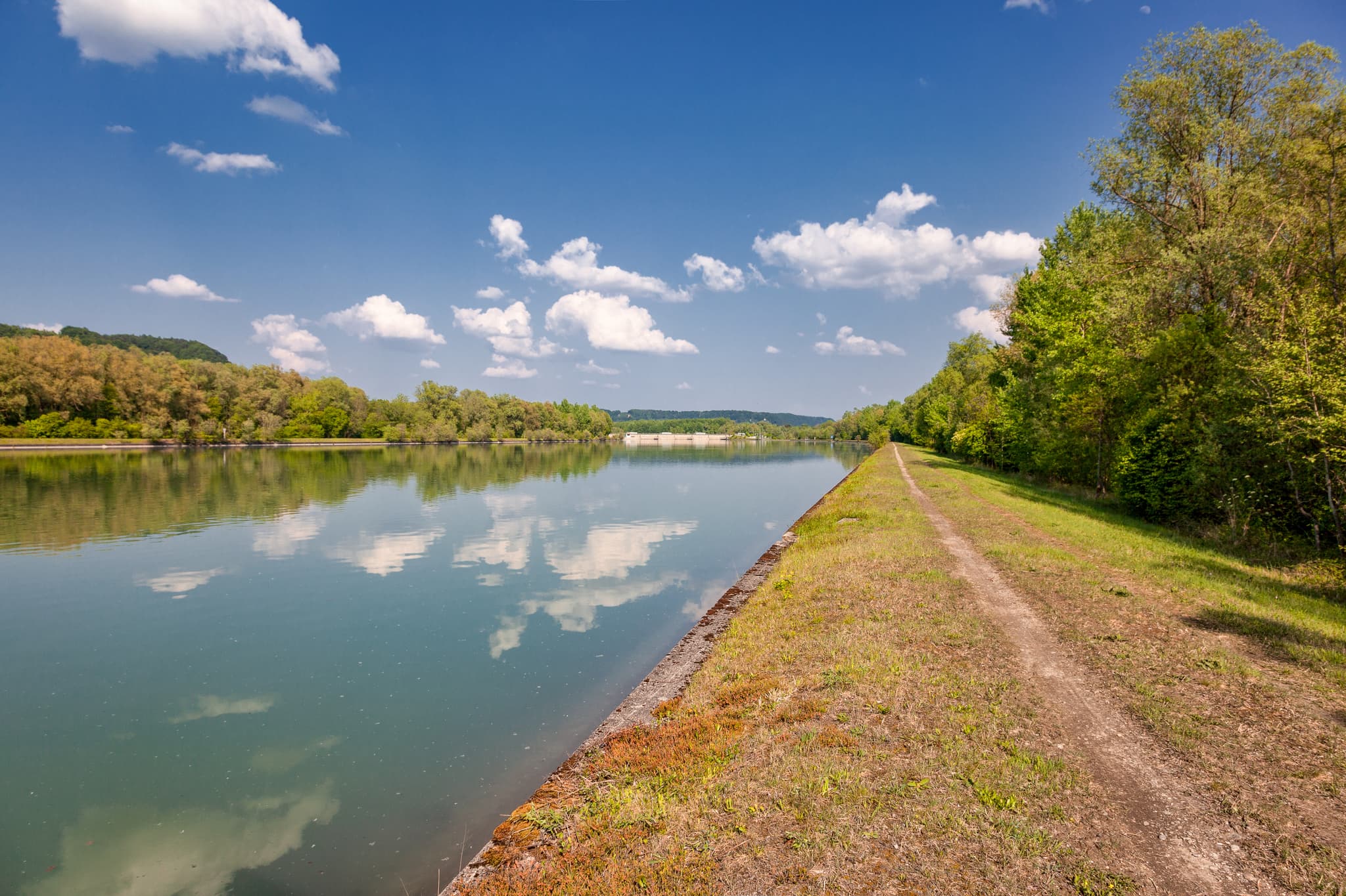 Der Radweg am Inn Kraftwerk Perach bei Neuötting im Landkreis Altötting, Oberbayern, Deutschland. Zeigt ruhige Flusslandschaft Inn-Salzach mit grünen Ufern.