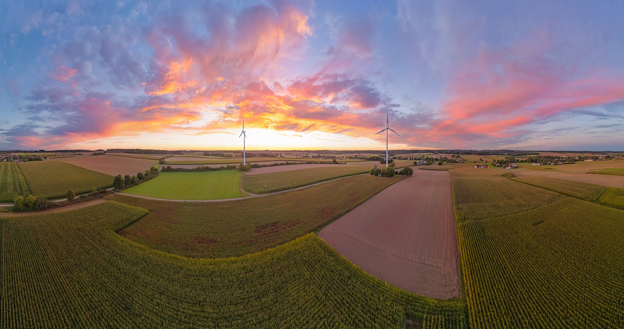 Panorama des Windparks Dirnaich, Gangkofen, Landkreis Rottal-Inn, Niederbayern. Agrarlandschaft im Holzland mit Feldern und Windrädern bei Sonnenuntergang.