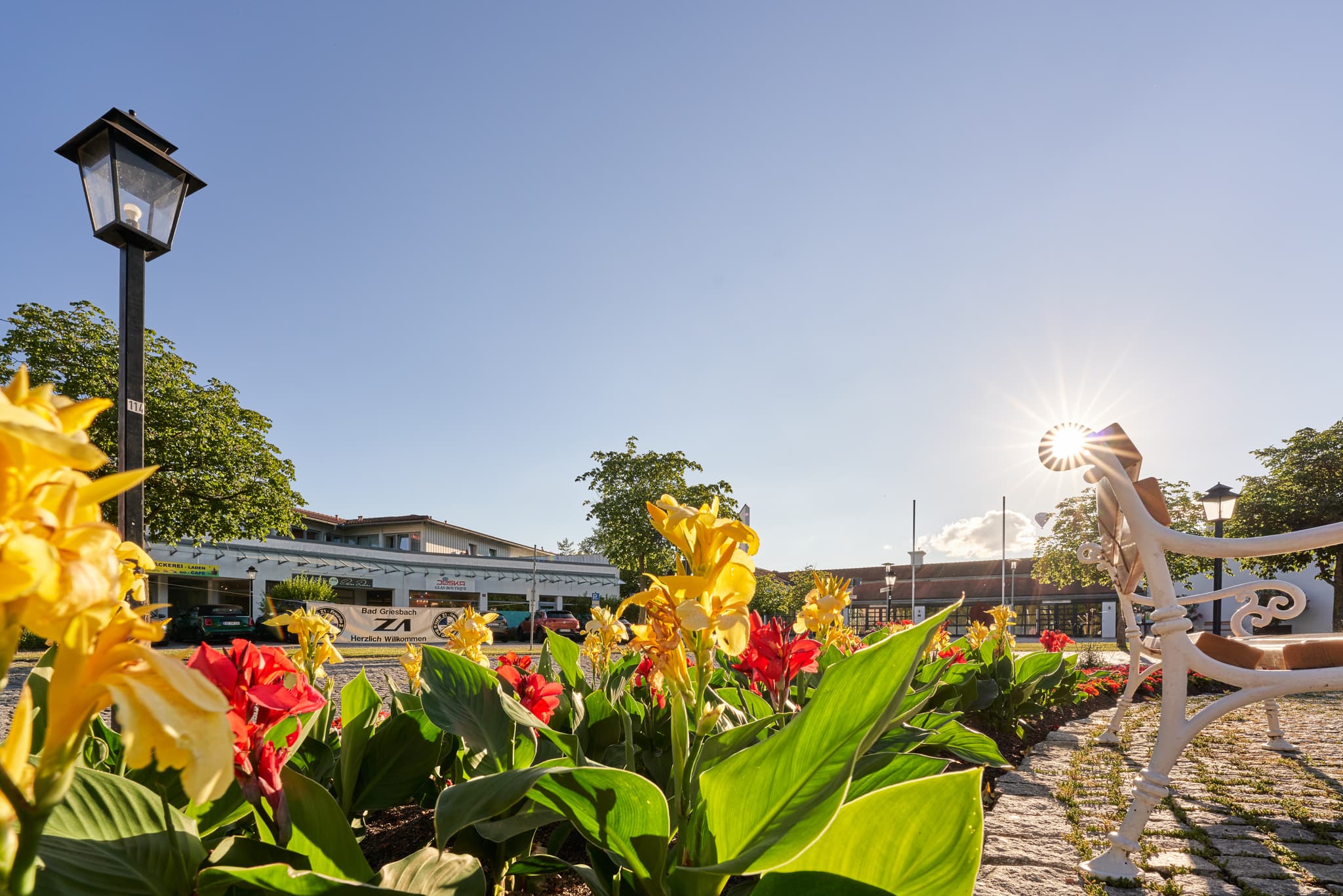 Blumenbeete am Kreisverkehr Brunnen Kurallee, Bad Griesbach, Passau, Niederbayern, Deutschland. Parkbank und Laterne zieren diesen Ort im Bayerischen Wald.