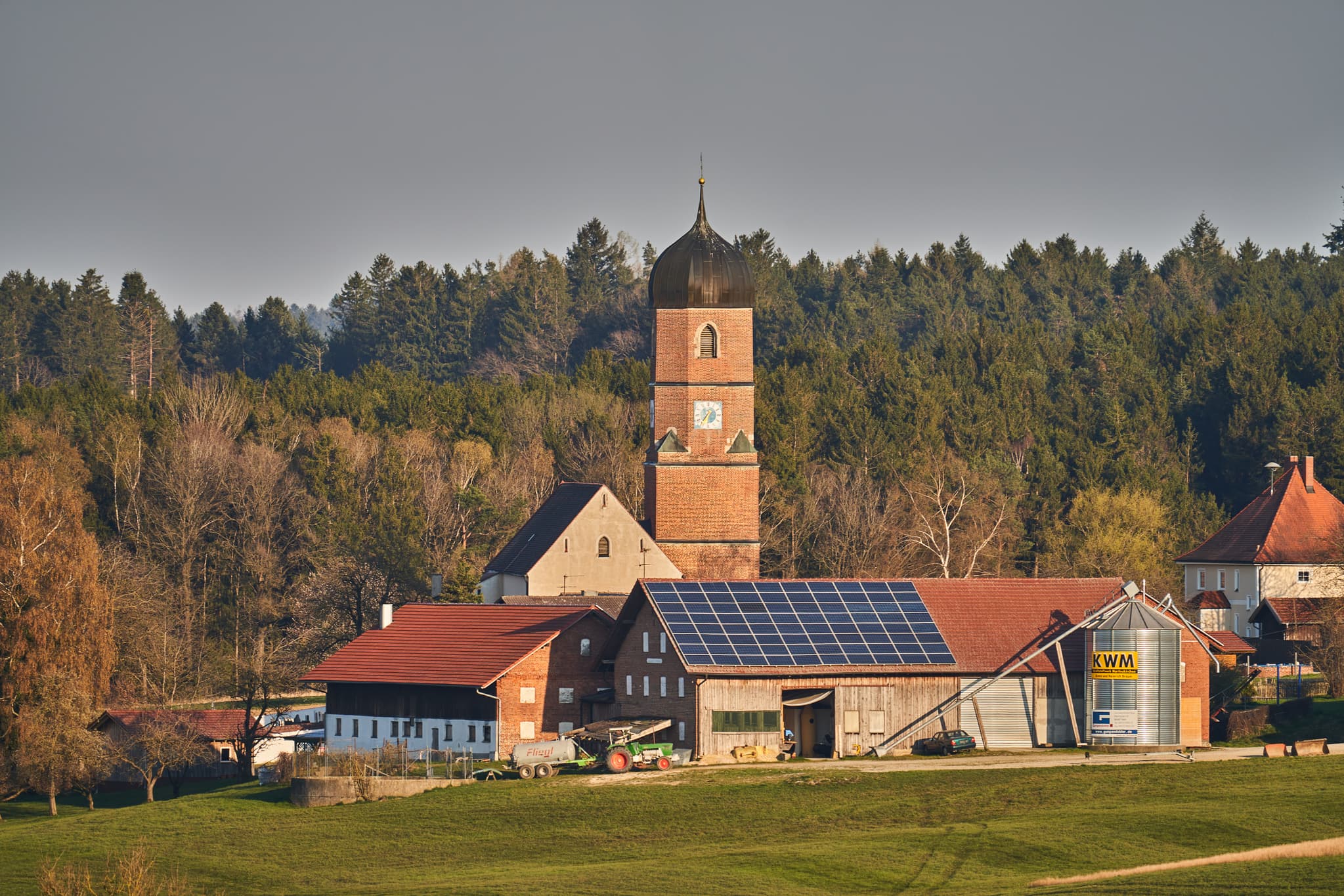 Kirche und Bauernhöfe mit Solaranlagen in Martinskirchen, Wurmannsquick, Landkreis Rottal-Inn, Niederbayern. Typische Landschaft des Holzlands, Deutschland.