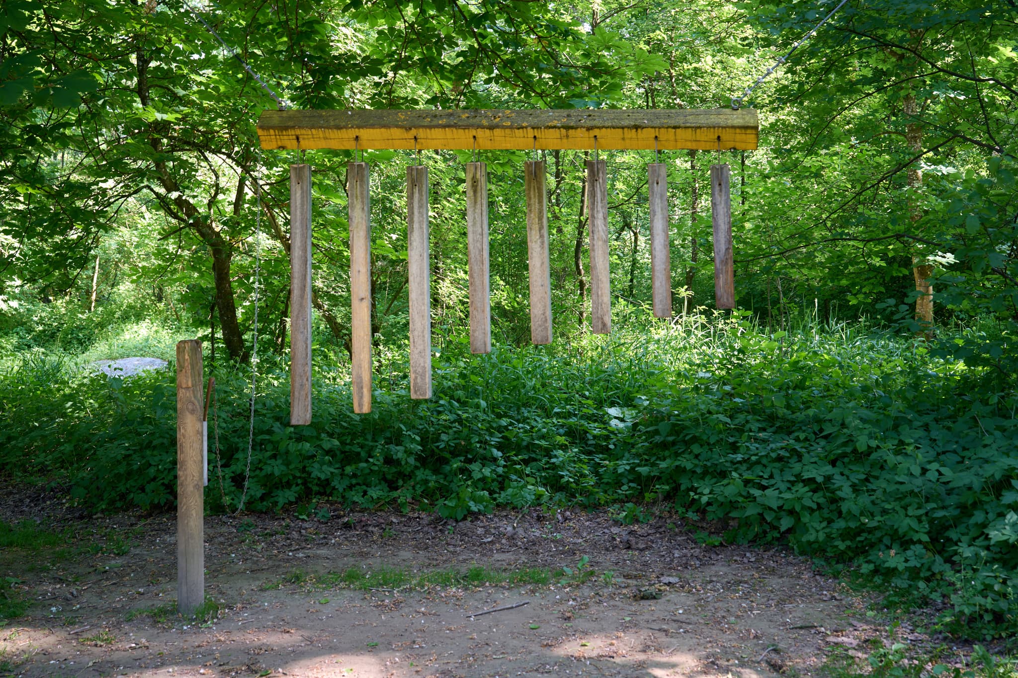 Naturerlebnisweg Innaue in Mühldorf, Mühldorf am Inn, Oberbayern, Deutschland. Ein Holzklangspiel steht inmitten einer grünen Waldlandschaft.