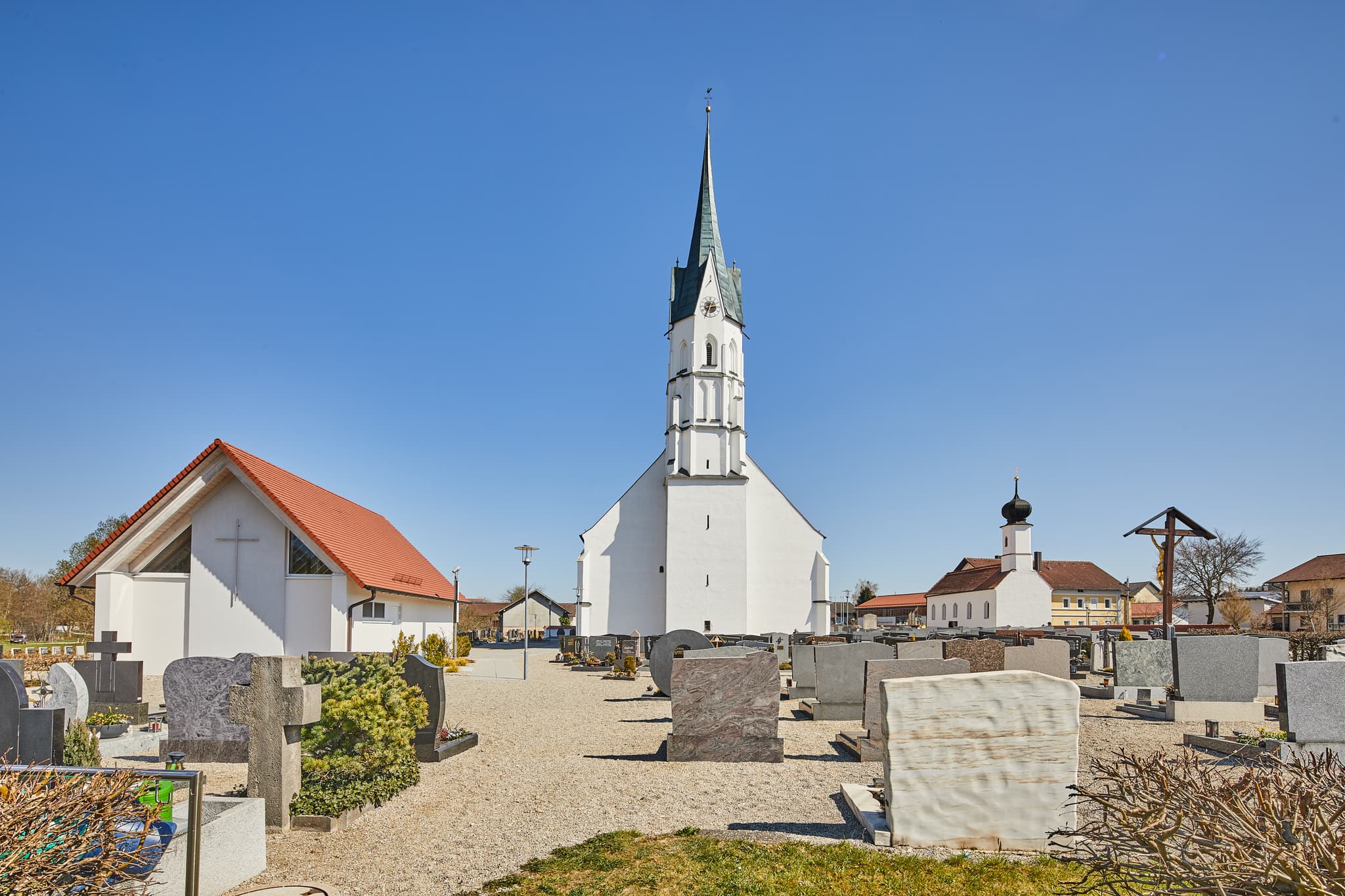 Markante Kirche mit Friedhof in Unterdietfurt, Landkreis Rottal-Inn, Niederbayern. Die Szene liegt im bayerischen Holzland, Deutschland, unter klarem Himmel.