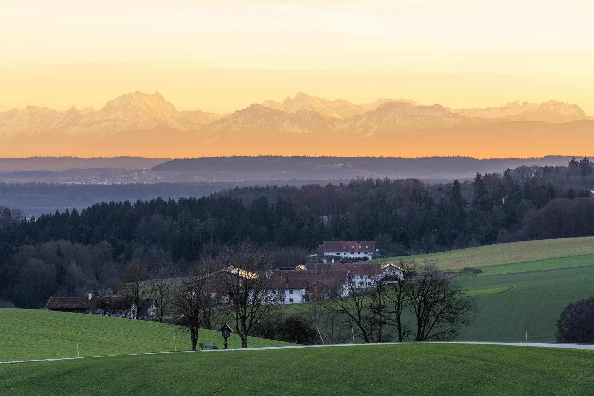 Blick aus Haizing, Erlbach, Altötting, Oberbayern. Die ländliche Inn-Salzach-Landschaft mit Gehöften, Feldern und Hügeln erstreckt sich vor Alpenkulisse.