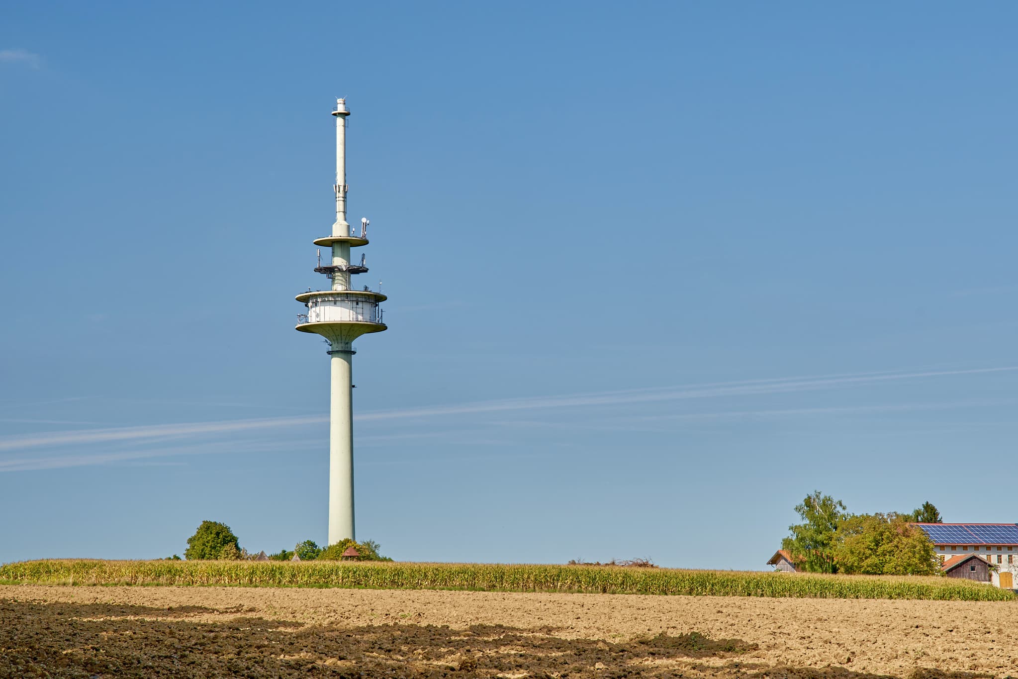 Funkturm bei Schnaitsee, Landkreis Traunstein, Oberbayern. Die ländliche Chiemgauer Landschaft in Deutschland mit Ackerland unter blauem Himmel ist zu sehen.