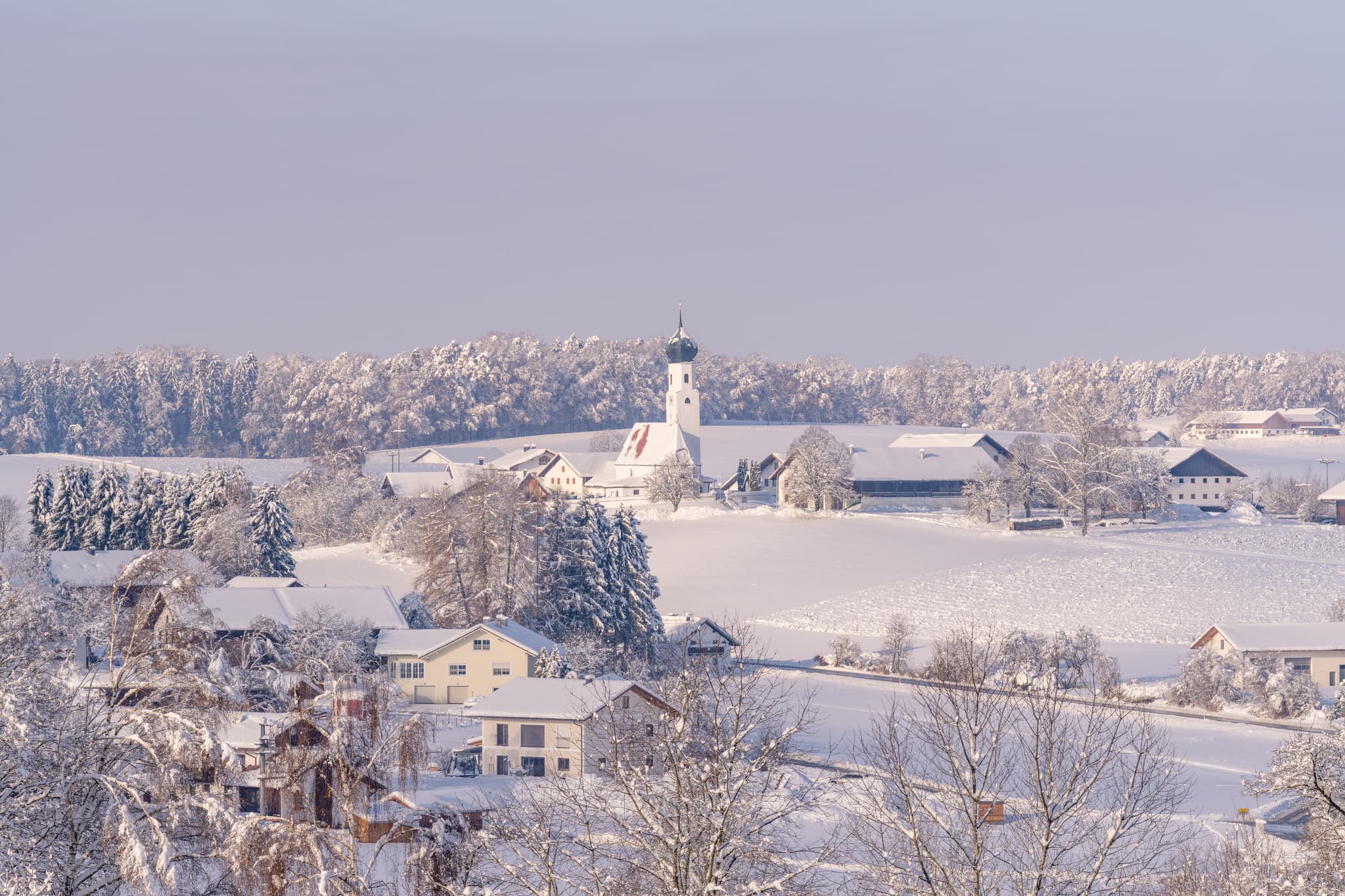 Verschneite Winterlandschaft in Eisenbuch, Erlbach, Landkreis Altötting, Oberbayern. Region Inn-Salzach, Deutschland. Motiv zeigt Dorf mit Kirche im Schnee.