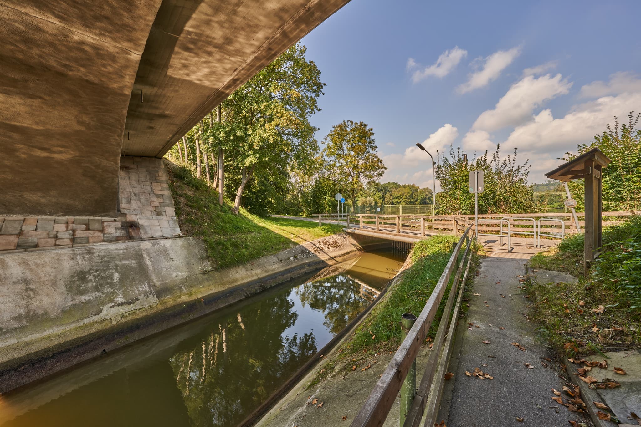 Unterführung am Enhofen Stauweiher Isen in Winhöring, Altötting, Oberbayern, Inn-Salzach, Deutschland. Brücke überspannt Kanal in grüner Natur.