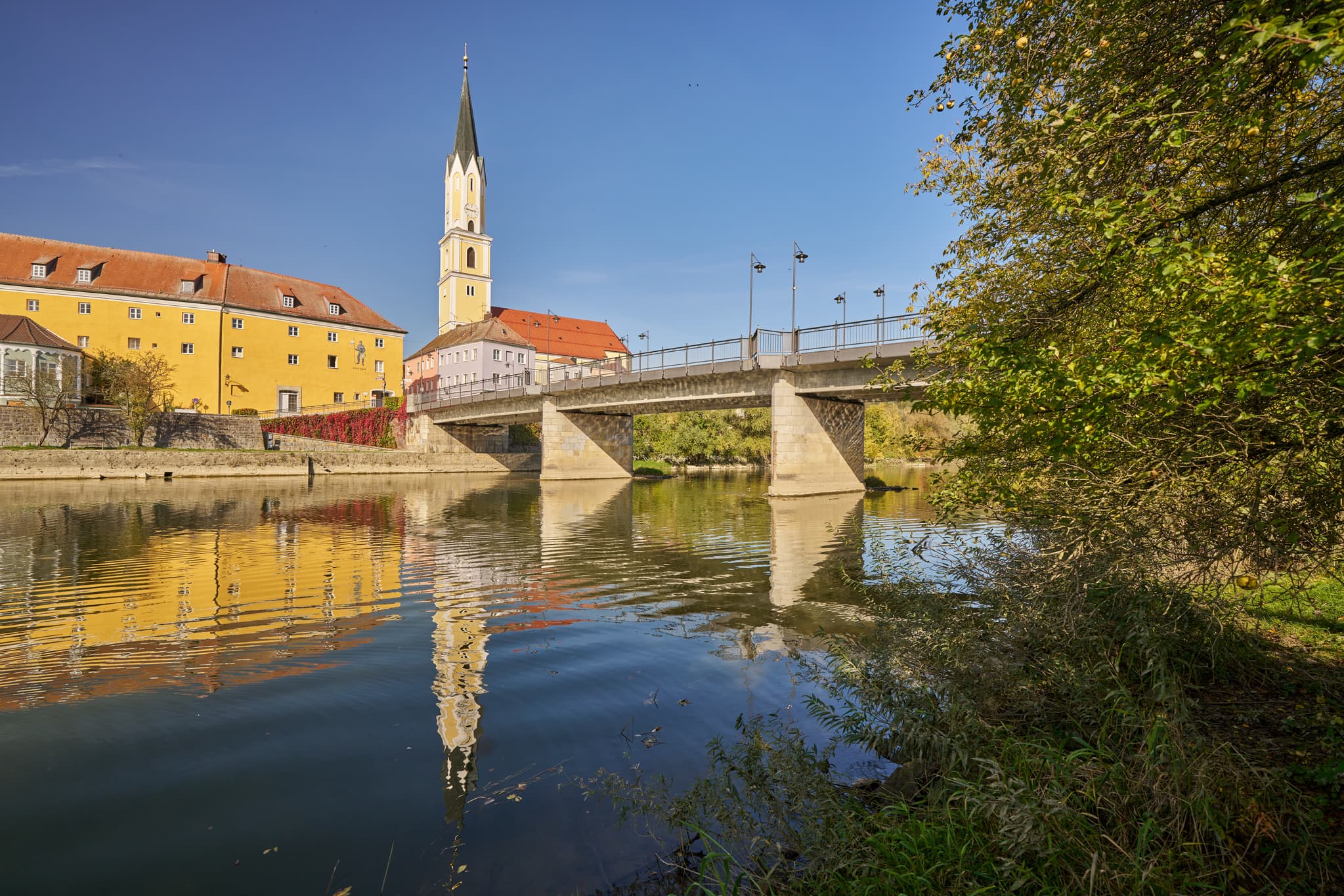 Stadtansicht Vilshofen an der Vils, Landkreis Passau, Niederbayern. Historische Gebäude, Kirchturm und Brücke spiegeln sich im Fluss. Donau-Wald, Deutschland.