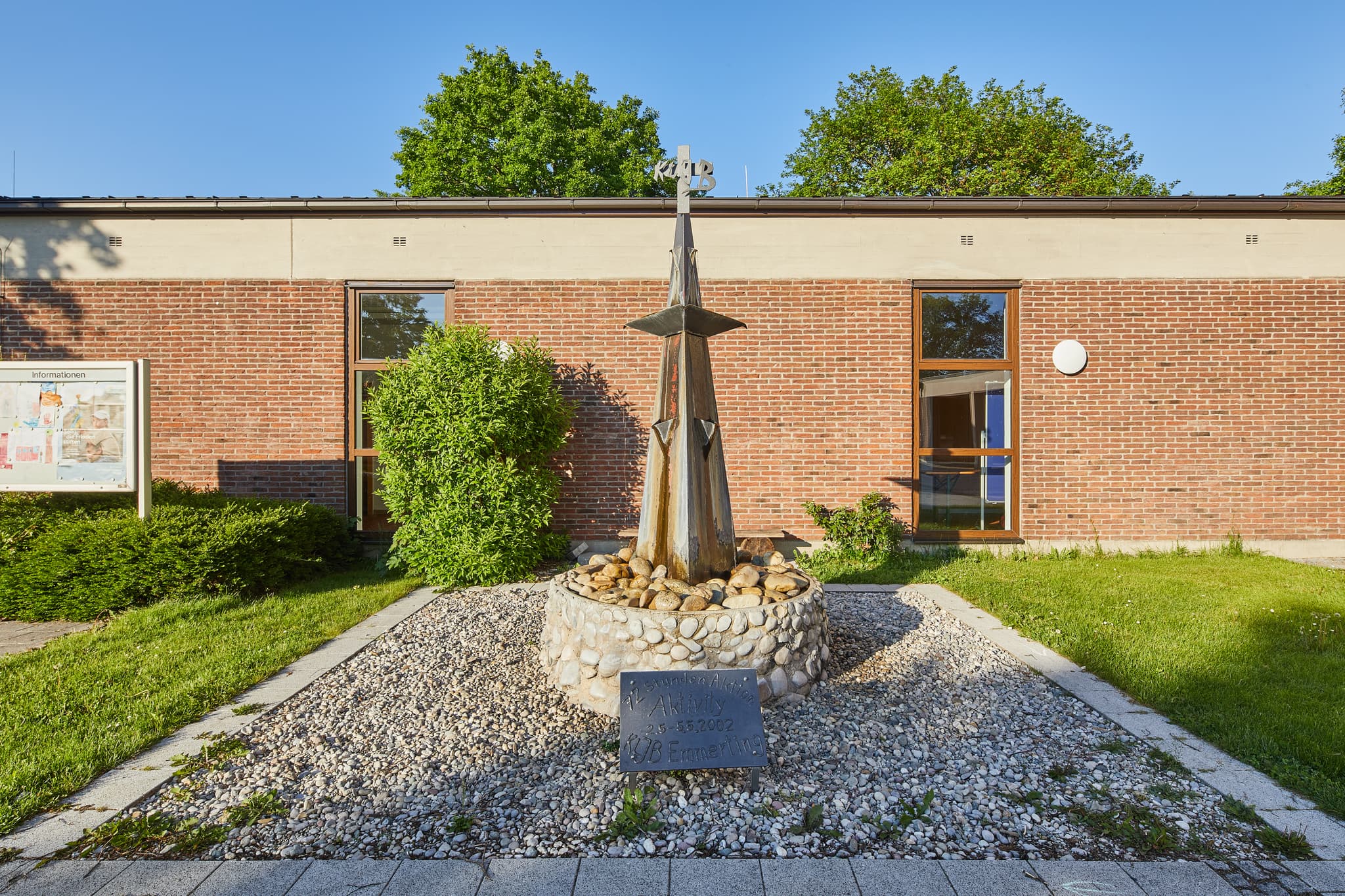 Brunnen am Dorfplatz in Emmerting, Altötting, Oberbayern. Das Motiv zeigt den Brunnen mit einem Gebäudehintergrund in der Region Inn-Salzach, Deutschland.