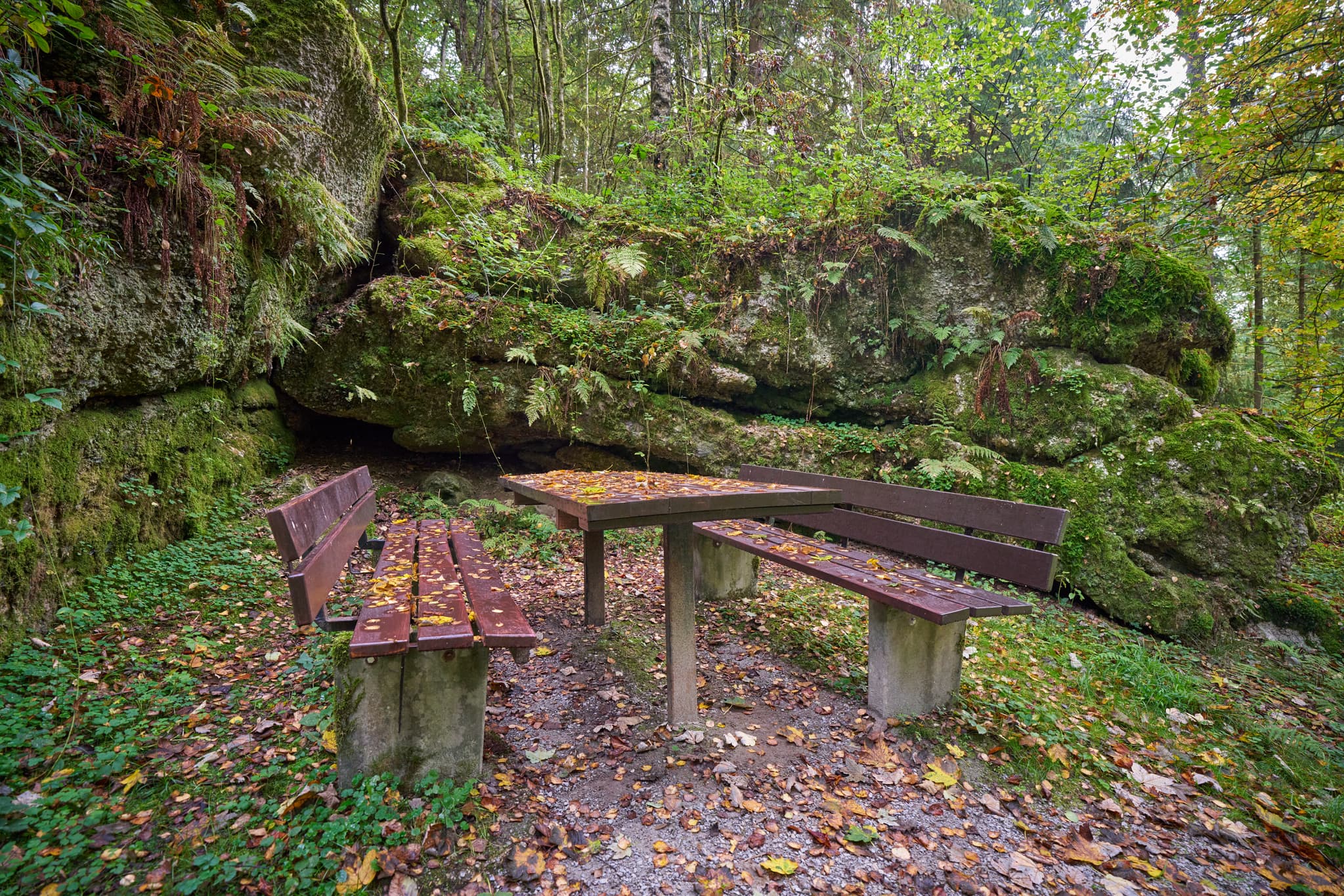 Picknicktisch und Bänke vor felsiger Felsformation im Wald. Bad Griesbach, Landkreis Passau, Niederbayern, Bayerischer Wald, Deutschland.