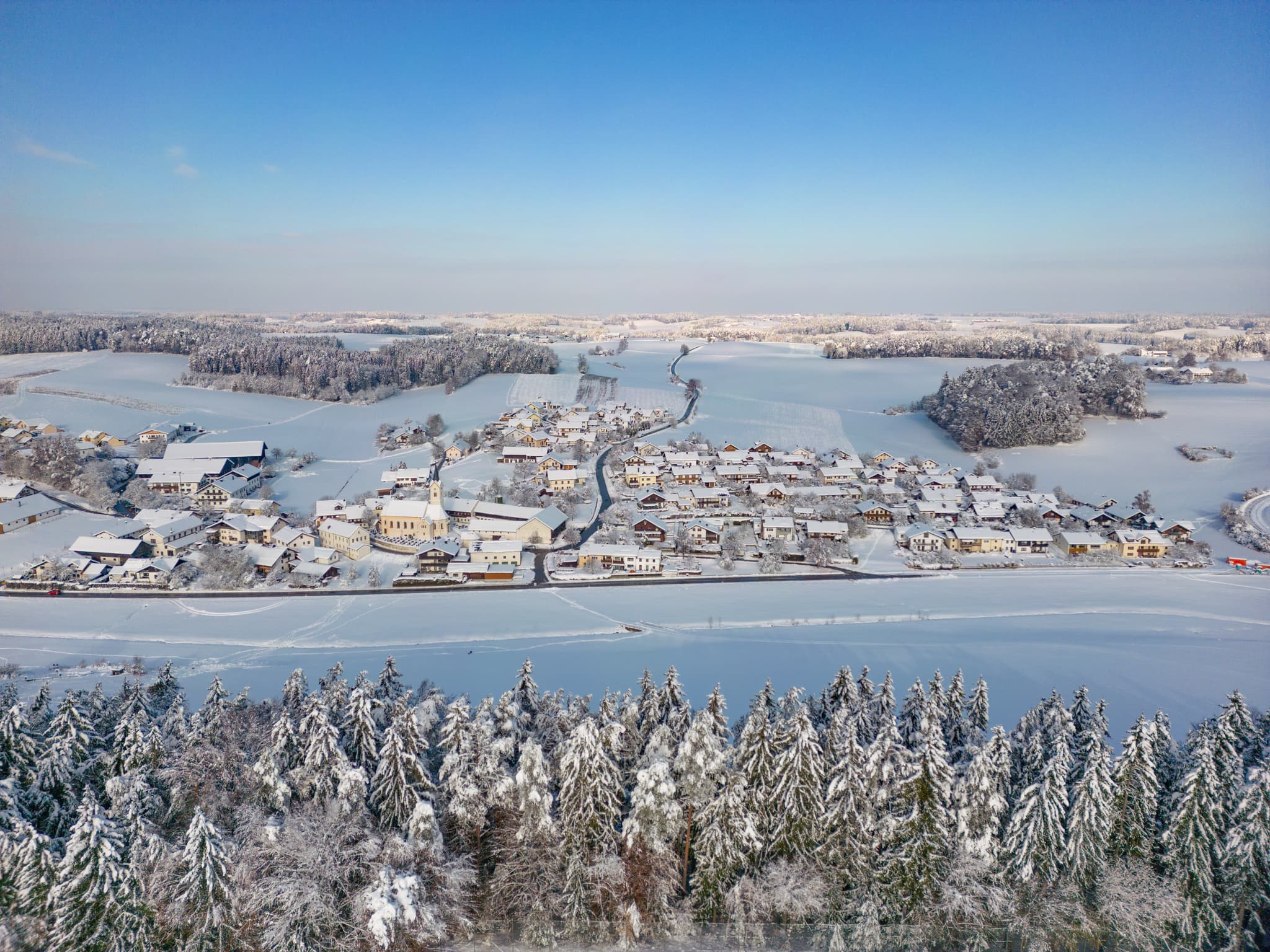 Luftbild Sportplatz Erlbach, Altötting, Oberbayern. Winterlandschaft Inn-Salzach Deutschland. Verschneite Felder, Wälder und Gebäude u nter blauem Himmel.