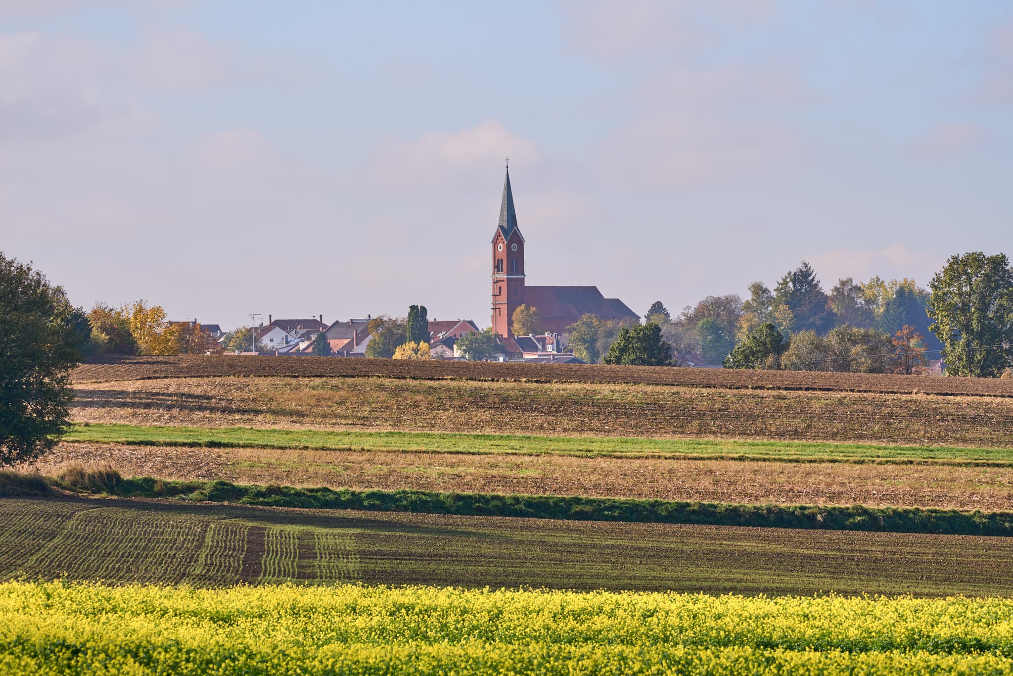 Ländliche Ortsansicht von Wurmannsquick, Rottal-Inn, Niederbayern, Deutschland. Zeigt die Pfarrkirche St. Andreas und Häuser mit Feldern im Holzland.
