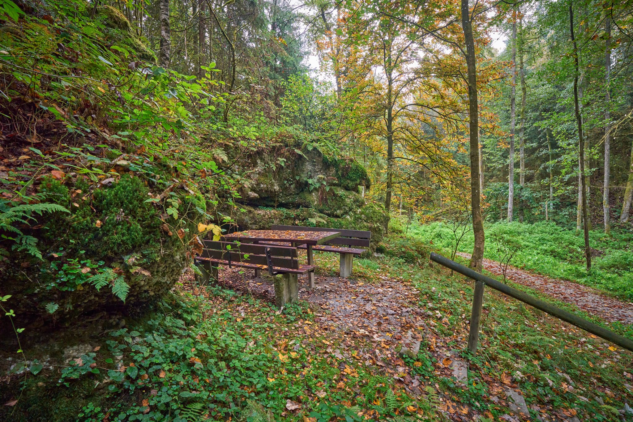 Picknicktisch und Bänke vor felsiger Felsformation im Wald. Bad Griesbach, Landkreis Passau, Niederbayern, Bayerischer Wald, Deutschland.