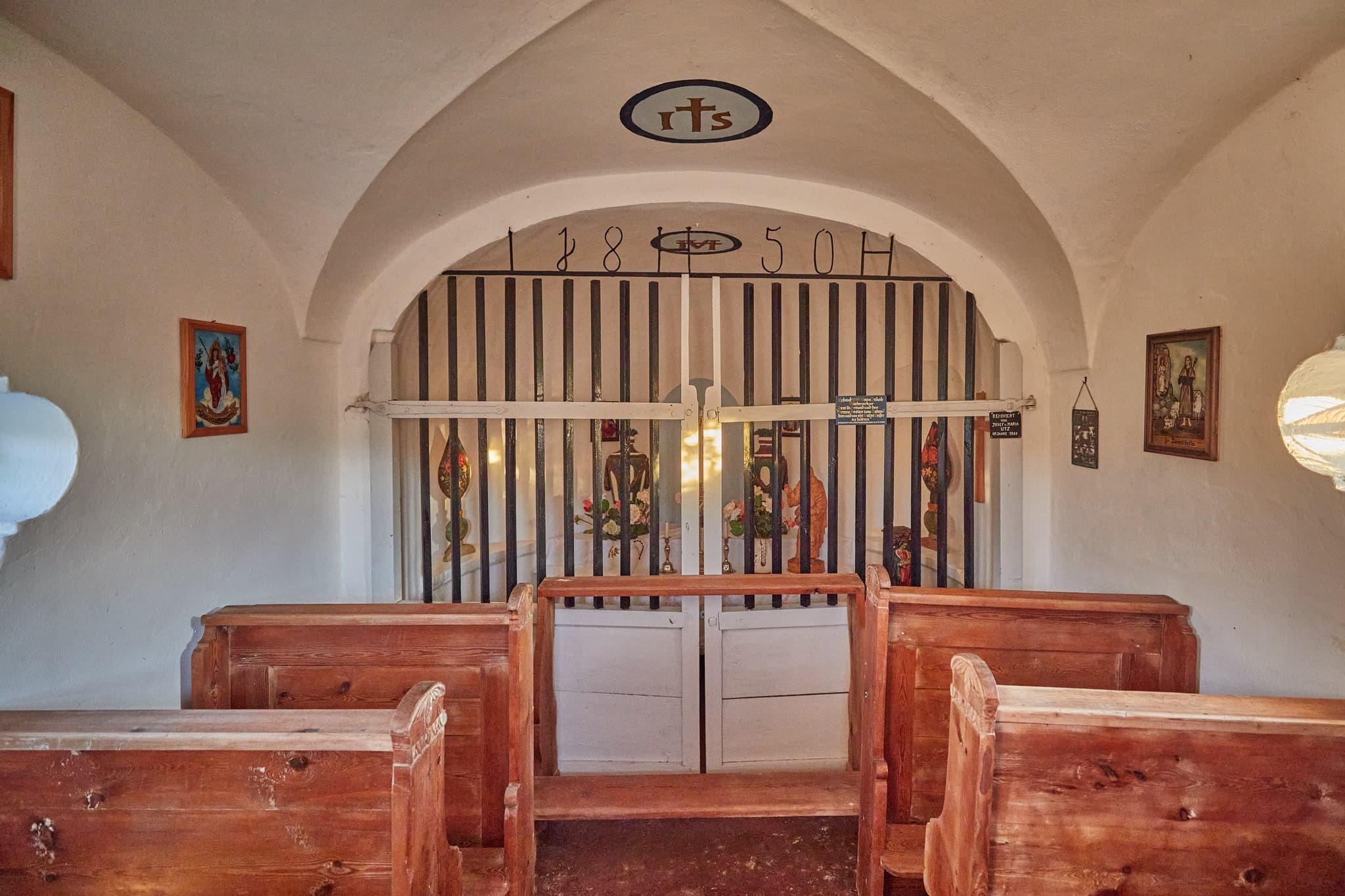 Kleine Backsteinkapelle im Abendlicht in Schildthurn bei Zeilarn, Landkreis Rottal-Inn, Niederbayern, Deutschland. Umgeben von grünen Wiesen und Bäumen.
