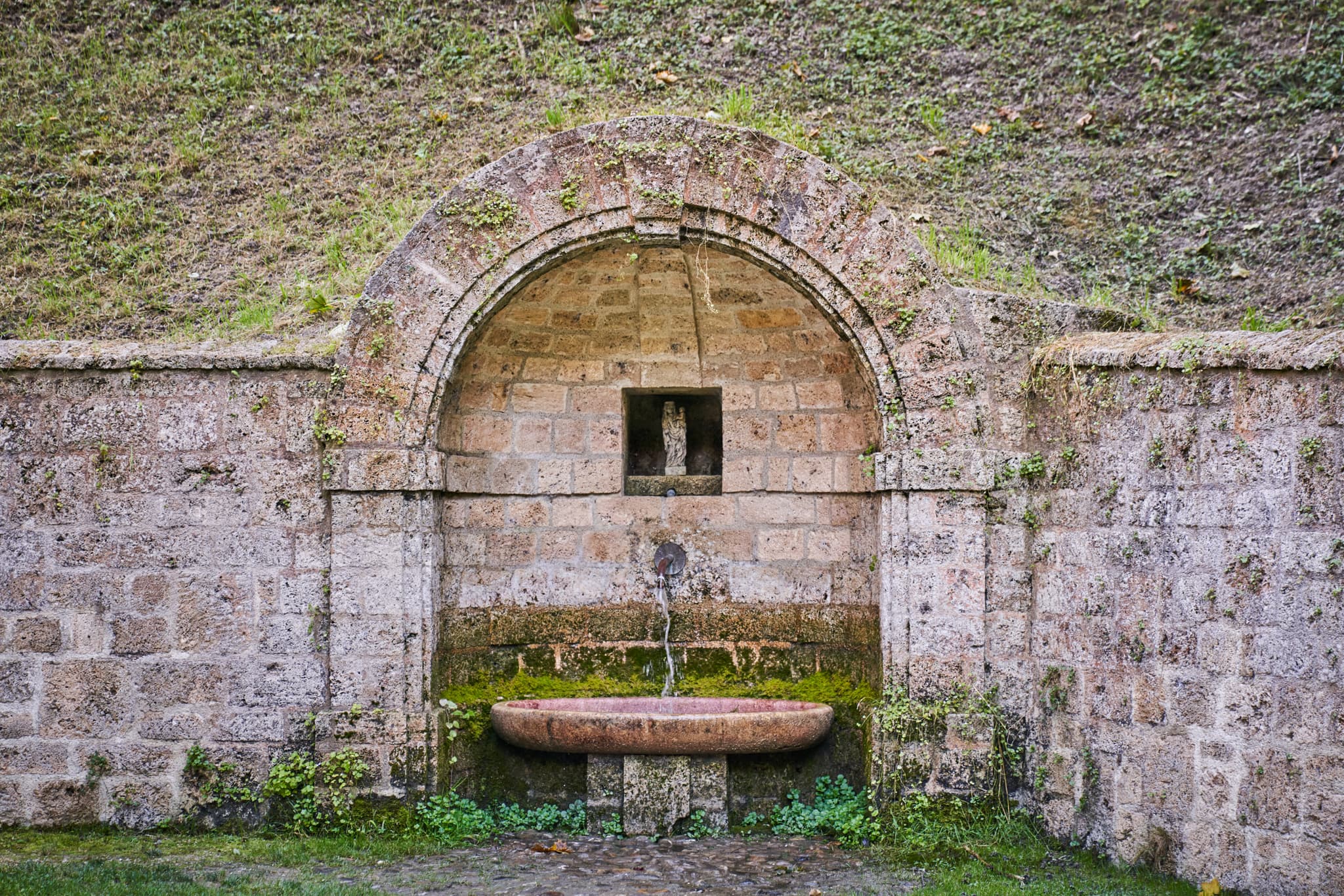 Historischer Steinbrunnen mit Rundbogen an der Ponlach Kapelle Maria Brunn, Tittmoning, Landkreis Traunstein, Oberbayern. Teil des Chiemgau in Deutschland.