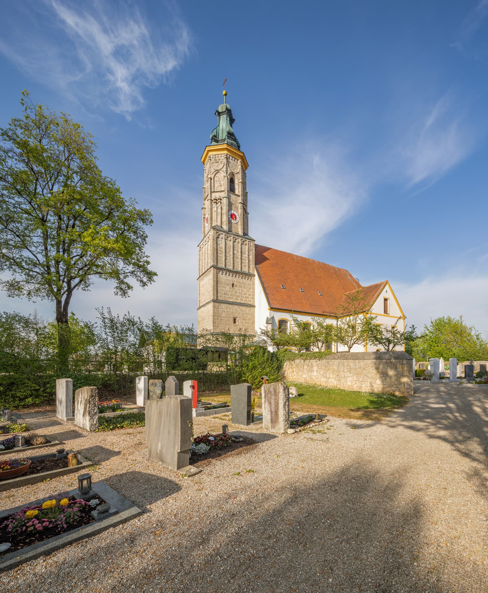 Margarethenberg Kirche in Hirten, Burgkirchen, Altötting, Oberbayern, Inn-Salzach, Deutschland. Außenansicht mit Turm und Friedhof bei blauem Himmel.