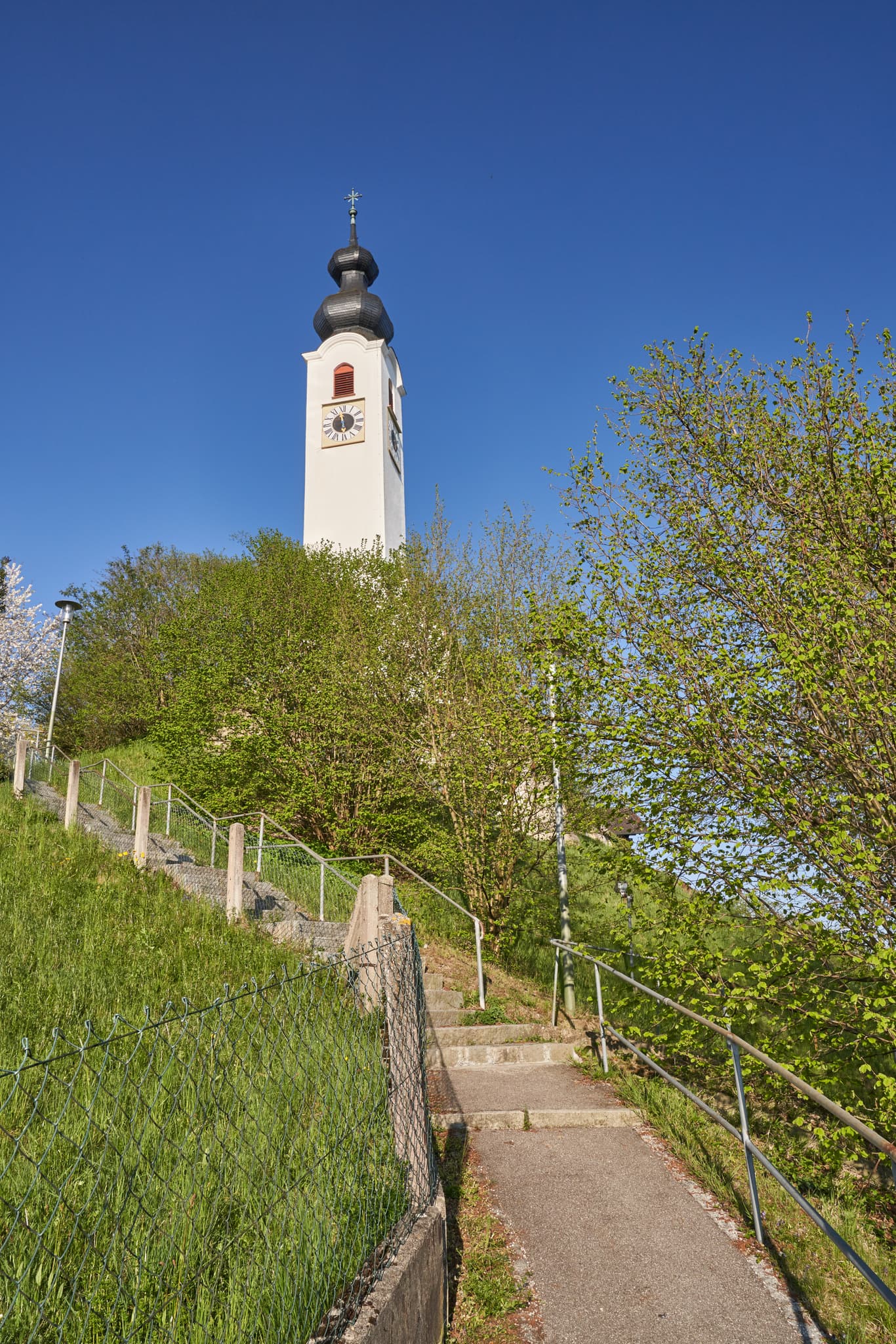 Die Pfarrkirche Mariä Himmelfahrt in Perach, Landkreis Altötting, Oberbayern. Eine Kirche auf Anhöhe mit Treppe, Inn-Salzach, Deutschland.