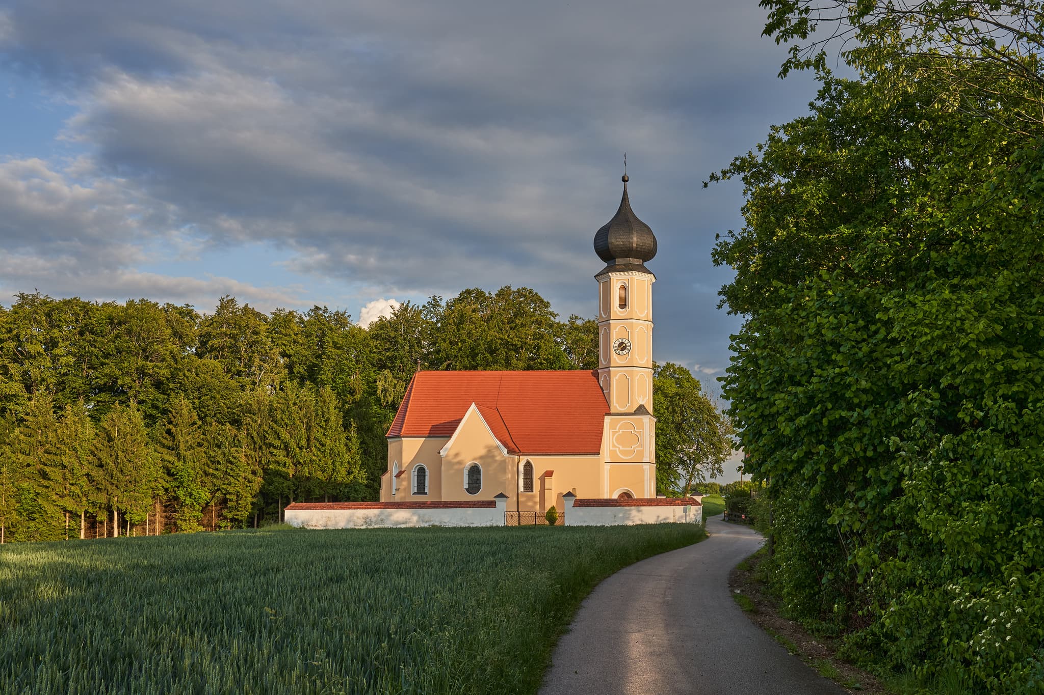 Foto der St. Sebastian Kirche in Leonberg, Oberbayern, Region Inn-Salzach, Idyllische Landschaft mit Feldern und Wald. Eingebettet in die Region Inn-Salzach.