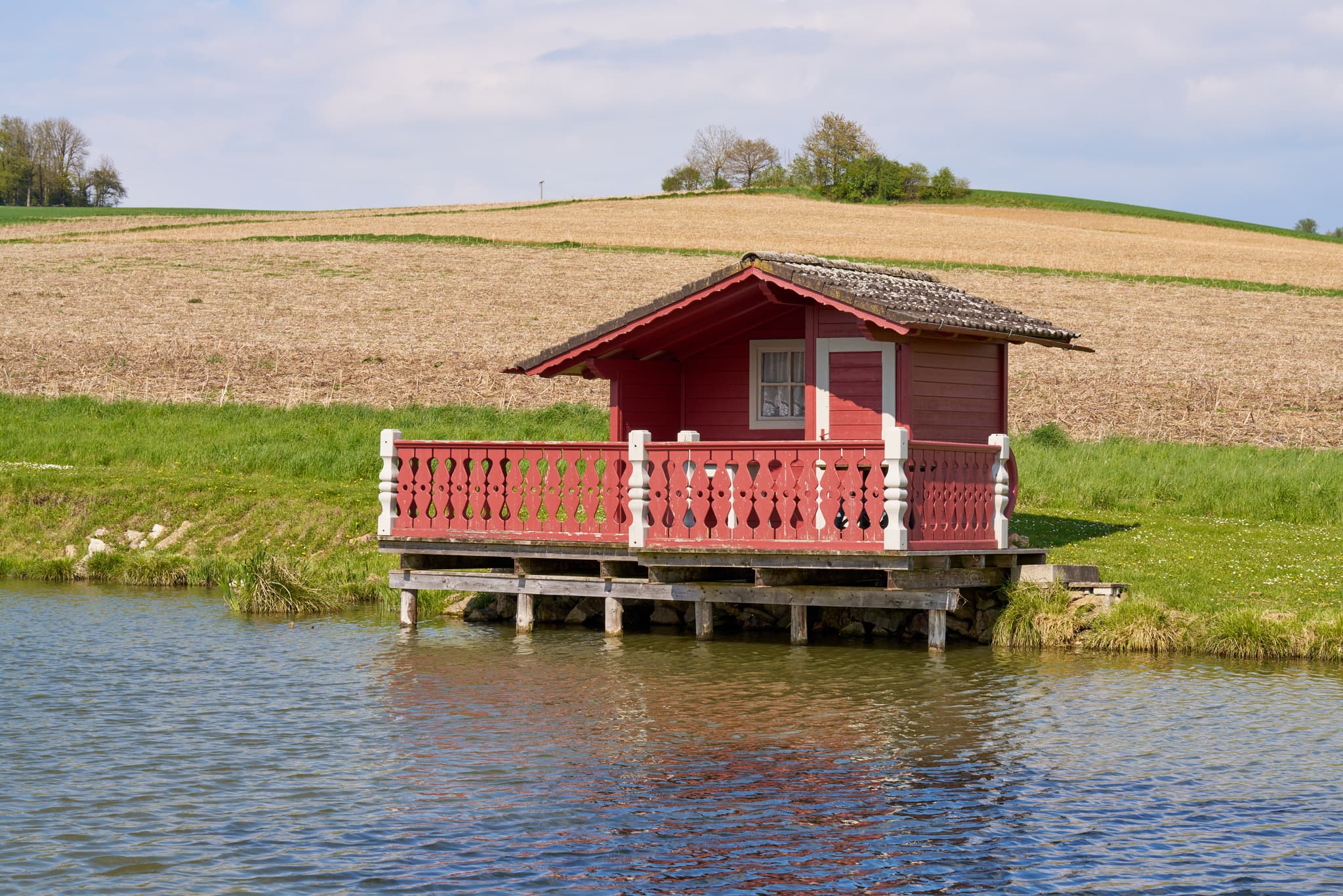 Idyllisches rotes Fischerhäuschen am Weng Badeweiher in Bad Griesbach im Landkreis Passau, Niederbayern, Deutschland. Malerische Landschaft im Bäderdreieck.