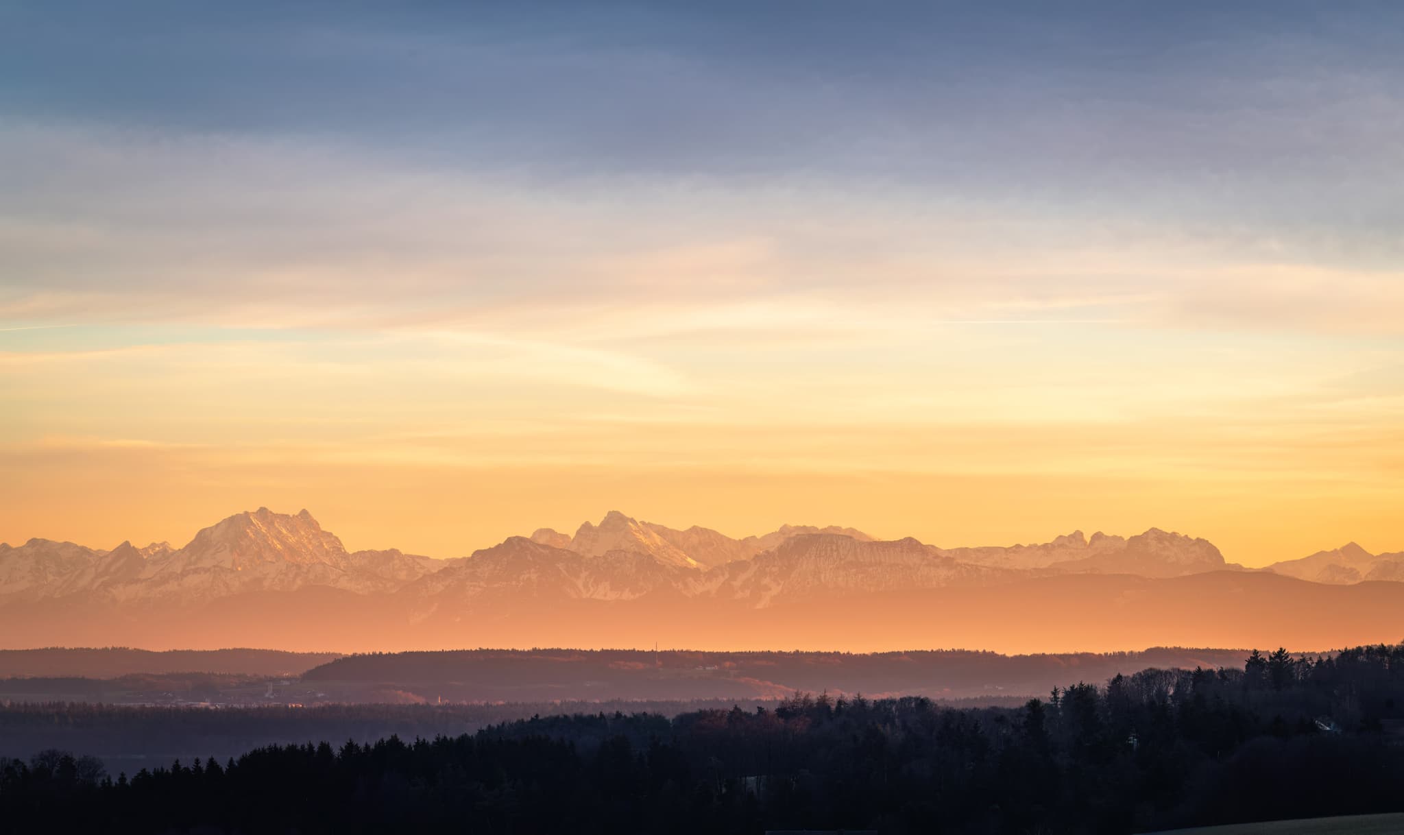 Blick aus Haizing, Erlbach, Altötting, Oberbayern. Die ländliche Inn-Salzach-Landschaft mit Gehöften, Feldern und Hügeln erstreckt sich vor Alpenkulisse.