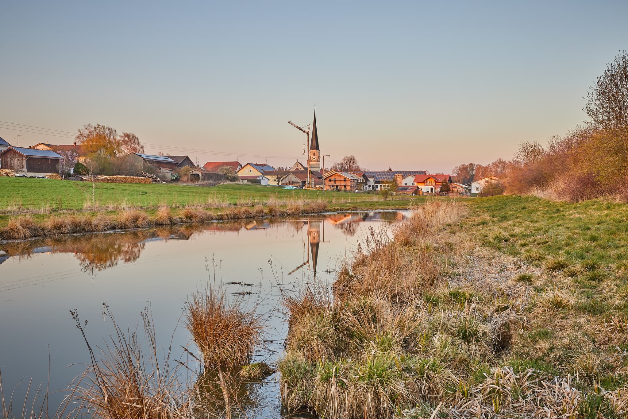 Friedlicher Teich mit Dorfkulisse Rogglfing, Gemeinde Wurmannsquick, Landkreis Rottal-Inn, Niederbayern, Deutschland. Idyllische Landschaft im Holzland.
