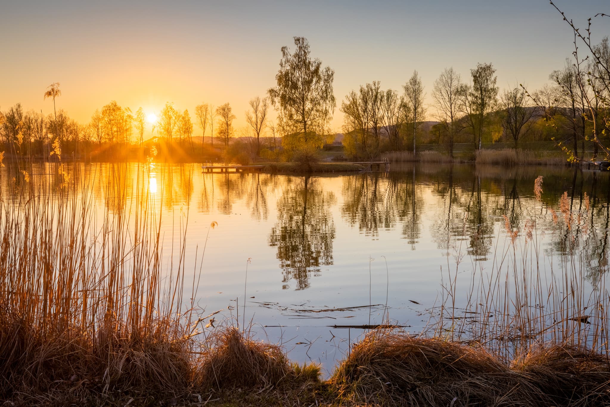 Abendlicher Sonnenuntergang am Badesee in Perach, Oberbayern, Inn-Salzach, Bayern, Deutschland. Idyllisches Naturbild.