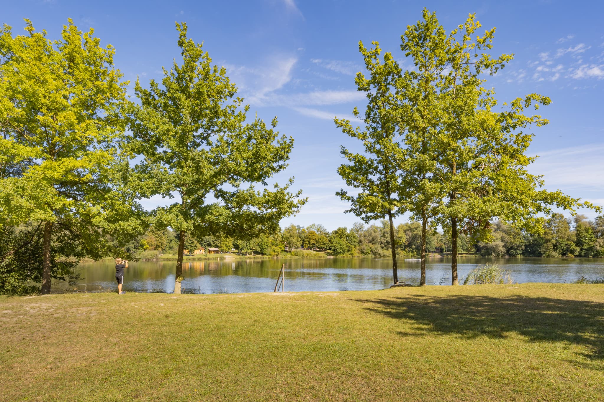 Sonniger Tag am Badesee bei Kirchdorf am Inn, Landkreis Rottal-Inn, Niederbayern. Gewässer der Region Bäderdreieck, Deutschland, mit Uferbäumen und Grün.