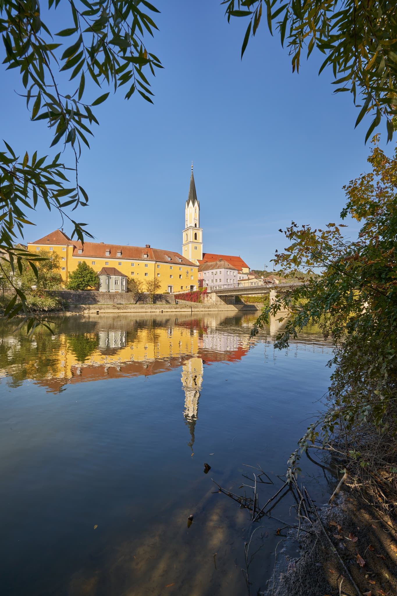 Stadtansicht Vilshofen an der Vils, Landkreis Passau, Niederbayern. Historische Gebäude, Kirchturm und Brücke spiegeln sich im Fluss. Donau-Wald, Deutschland.