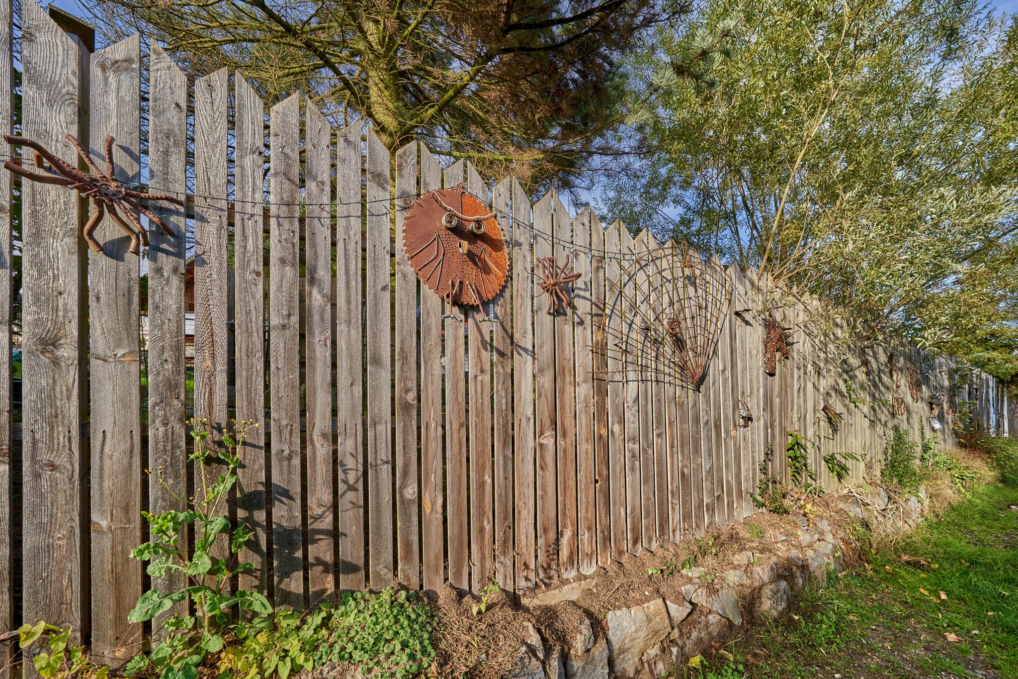 Holzlattenzaun mit Metallfiguren am Hörnieweg in Schönau, Landkreis Rottal-Inn, Niederbayern, Deutschland. Motiv in der Region Bäderdreieck bei Sonnenschein.