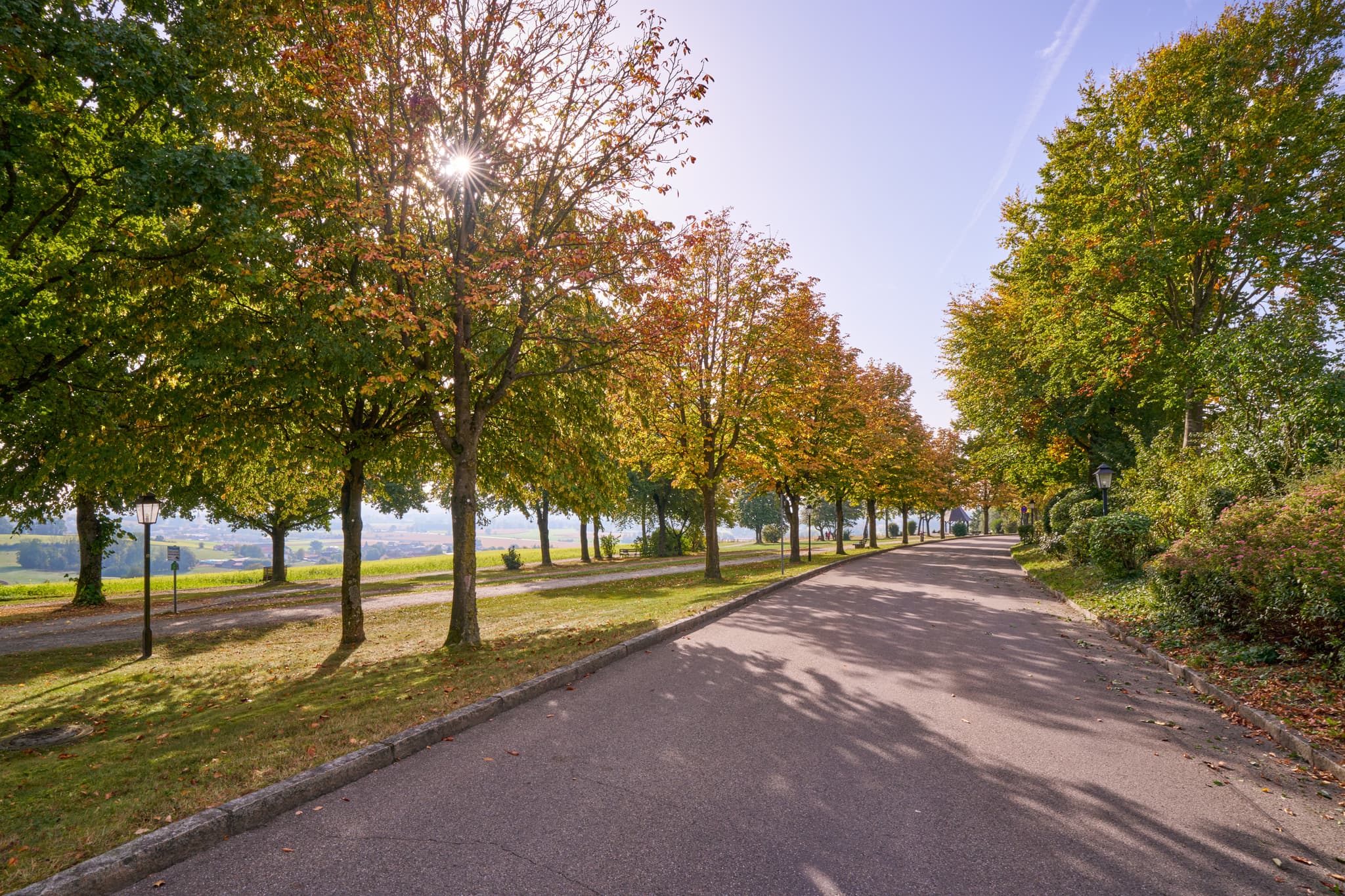 Idyllischer Herbst im Kurpark Bad Griesbach. Eine Allee mit farbenfrohen Bäumen führt durch die niederbayerische Bäderdreieck-Region in Deutschland.