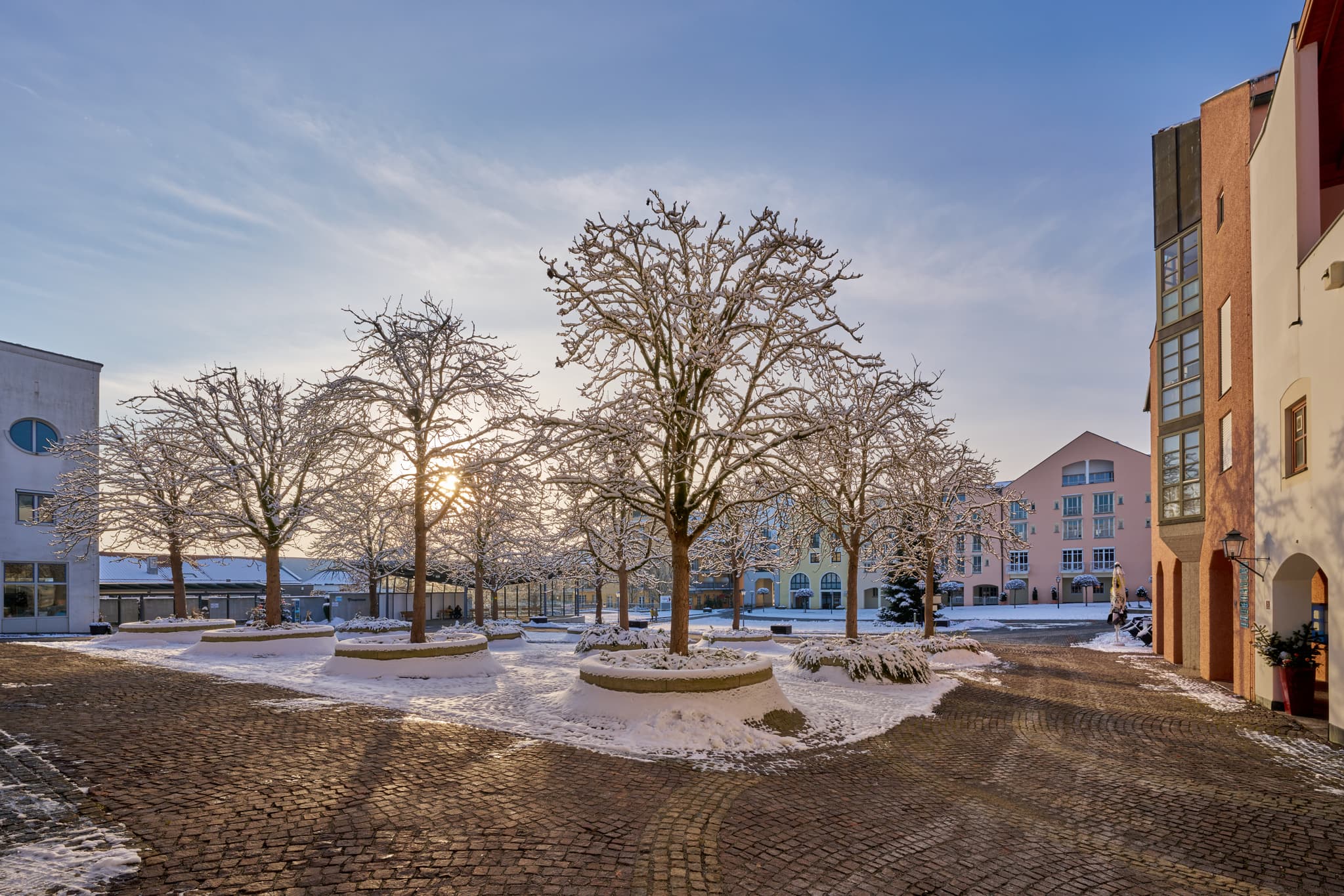 Winterlicher Kurplatz in Bad Griesbach im Rottal, Landkreis Passau, Niederbayern, Deutschland. Verschneite Bäume im Sonnenlicht, idyllische Winterlandschaft.