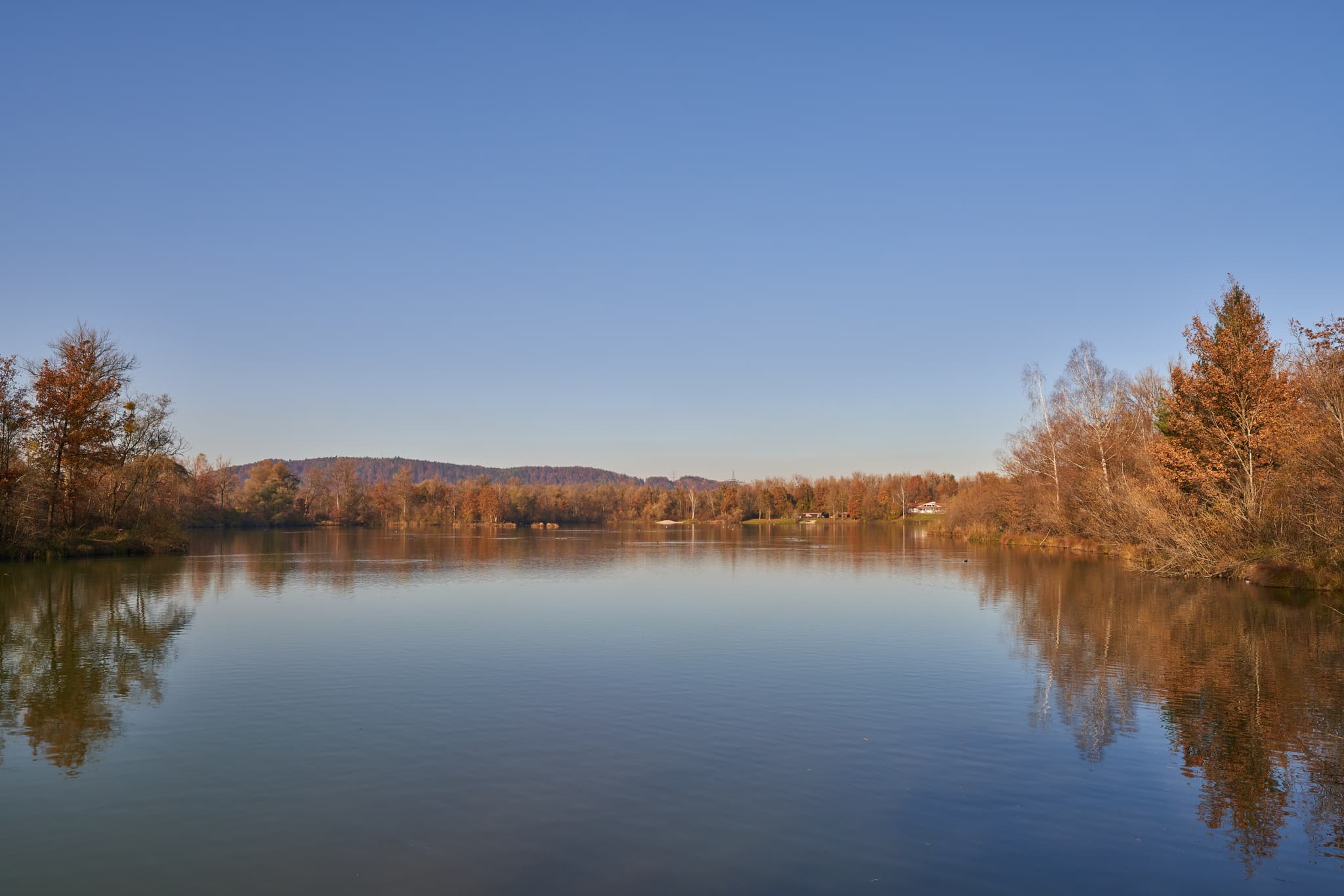 Idyllischer Waldsee Lago in Kirchdorf am Inn, Landkreis Rottal-Inn, Niederbayern. Herbstliche Bäume spiegeln sich auf dem Wasser.