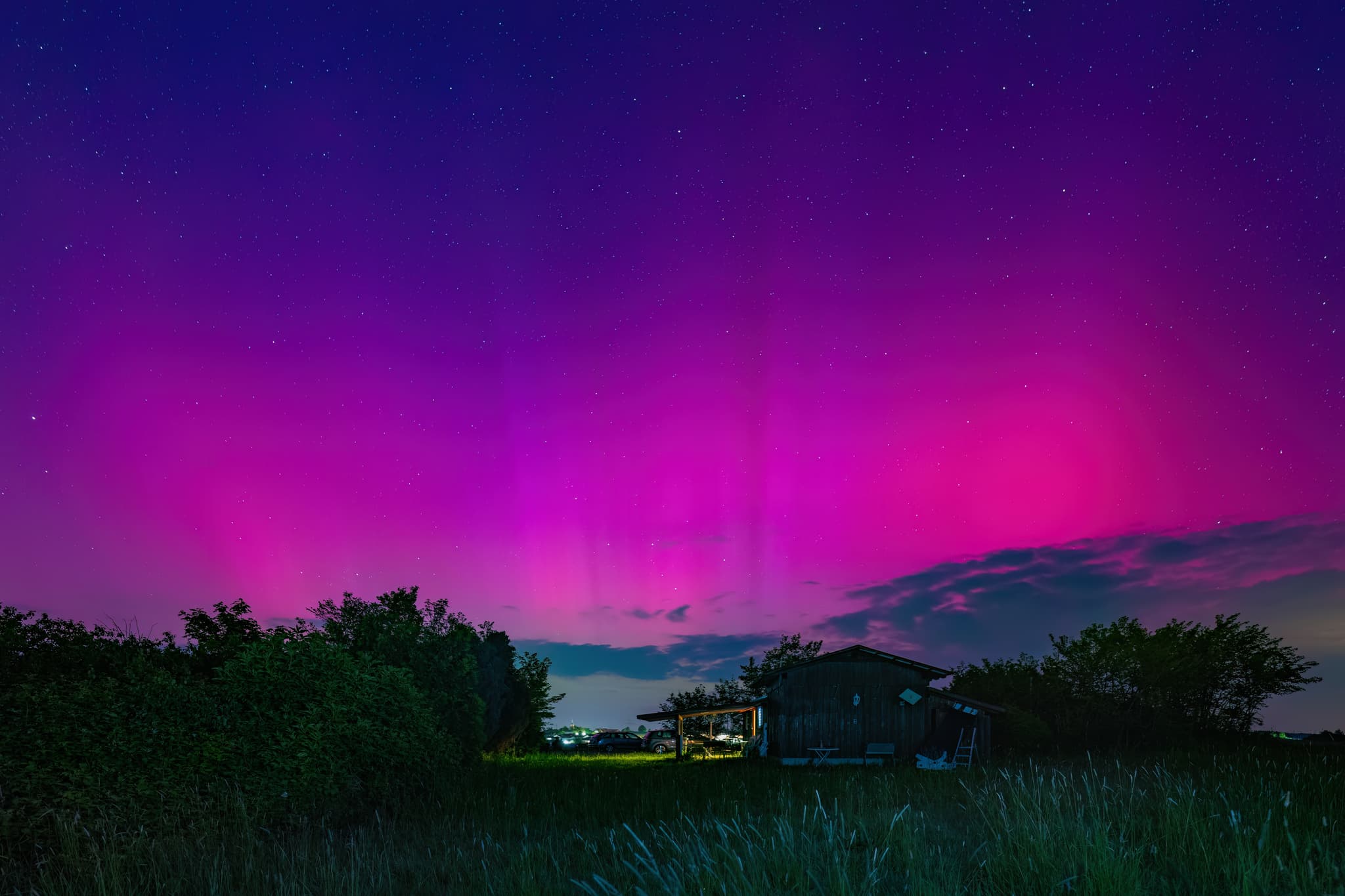 Polarlichter leuchten am Nachthimmel über Sternwarte, Wurmannsquick, Rottal-Inn, Niederbayern. Ländliche Szenerie mit Hütte, Feld im Holzland, Deutschland.